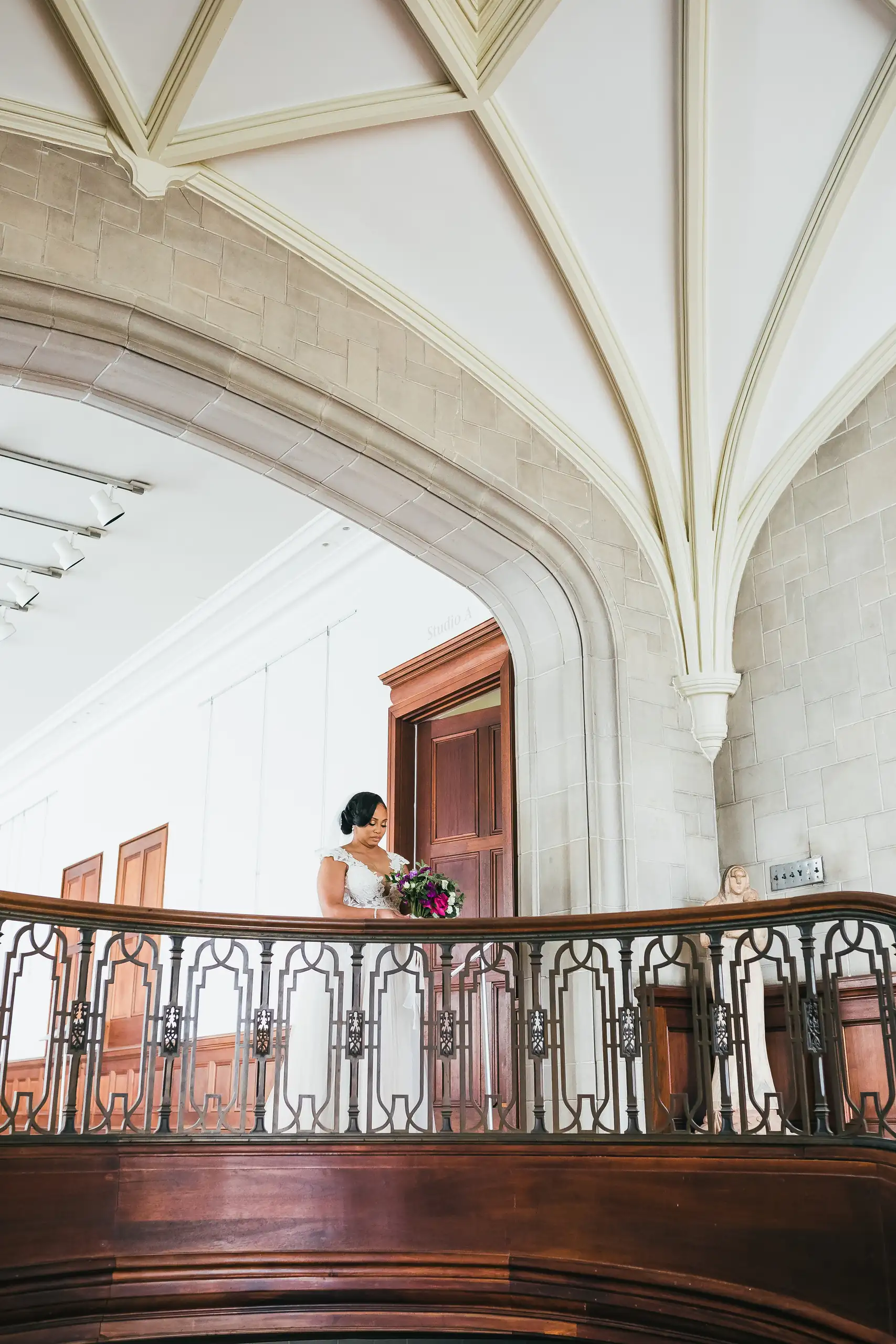 Bridal Portraits: the bride small on the balcony under the vaulted ceiling, at their wedding at Callanwolde Fine Arts Center in Atlanta, GA
