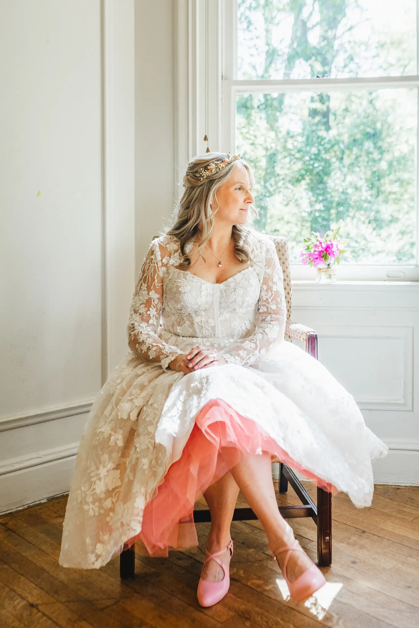 Bridal Portraits: the bride seated, her pink petticoat showing, at their wedding at Callanwolde Fine Arts Center in Atlanta, GA