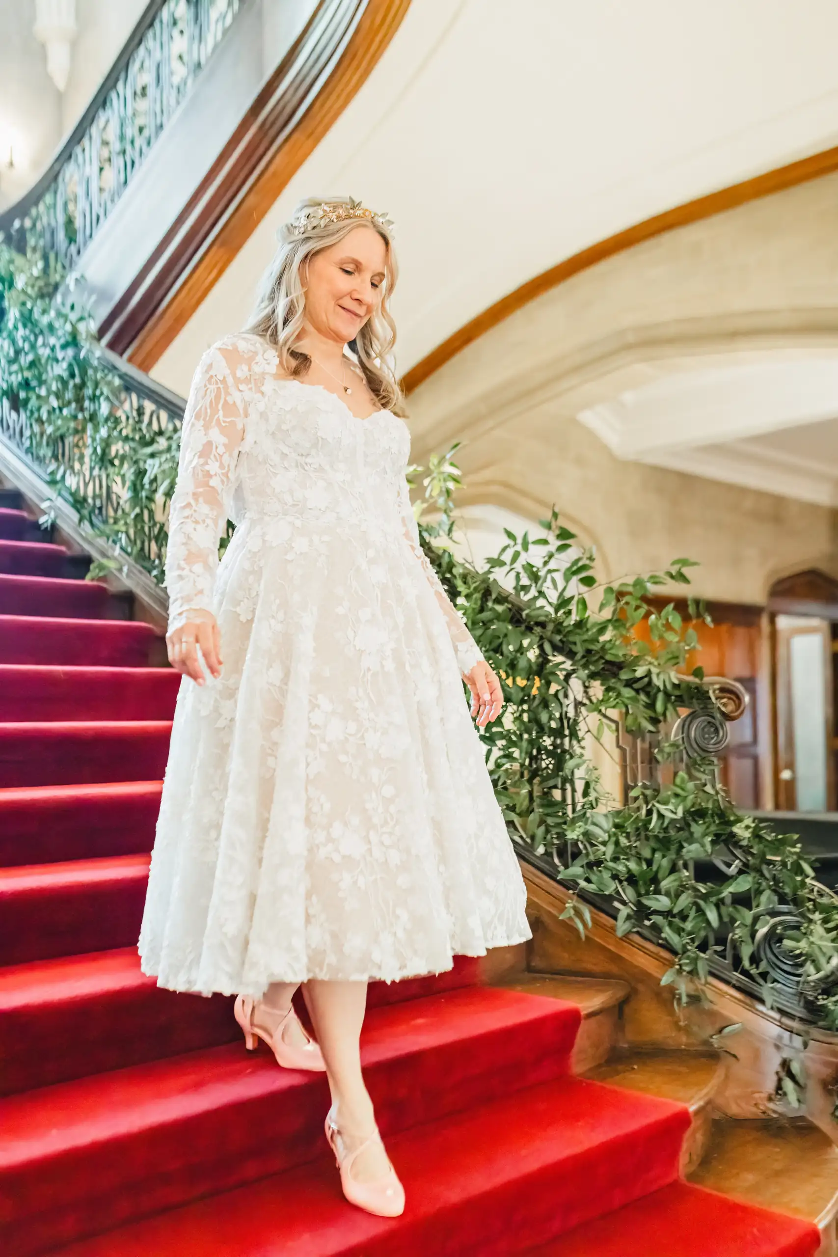 Getting Ready: the bride coming down the red staircase, before their wedding at Callanwolde Fine Arts Center in Atlanta, GA