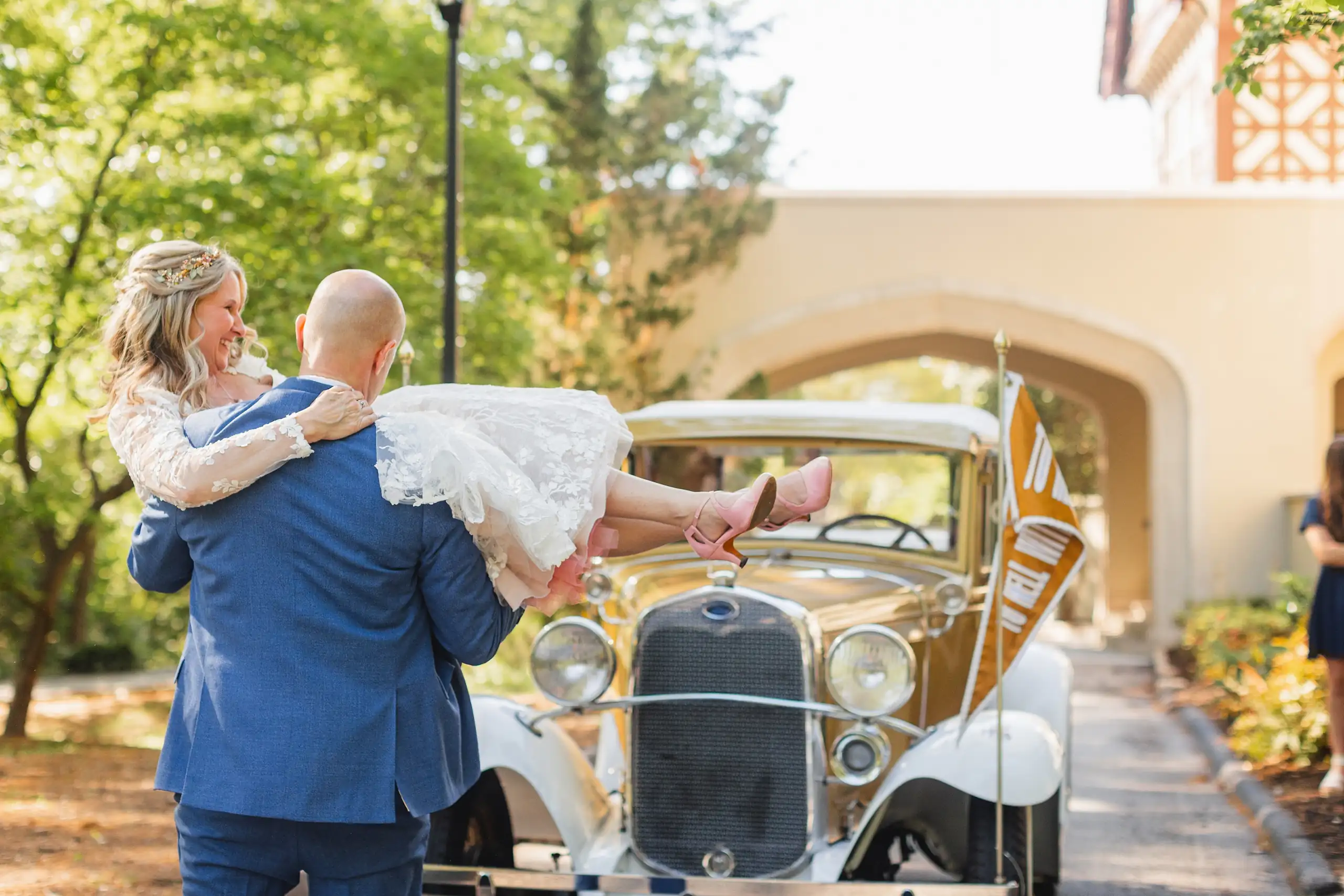 Send-Off: the groom lifting the bride into the Georgia Tech Ramblin' Wreck, at their wedding at Callanwolde Fine Arts Center in Atlanta, GA