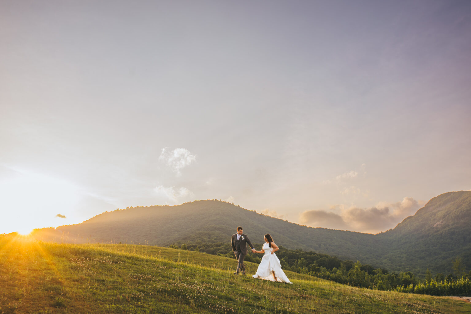 Bride and groom walking a sunset hillside at their Yonah Mountain Vineyards wedding, Cleveland