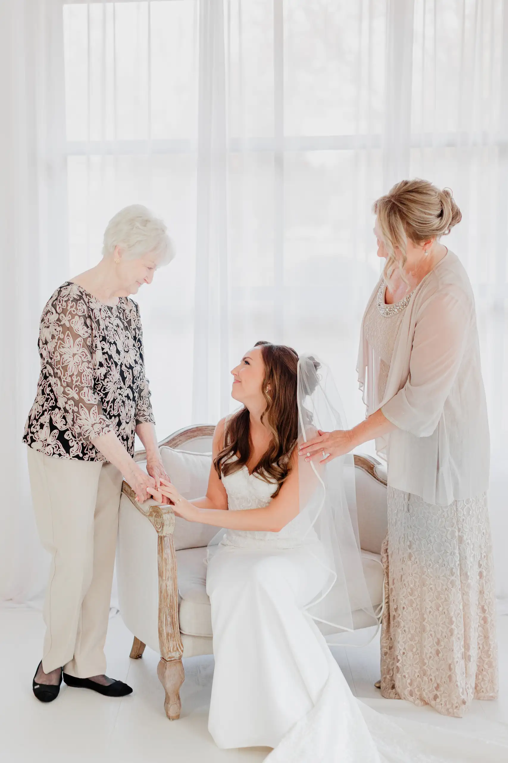Bridal Portraits: her mother and grandmother settling her gown, during her bridal portrait session