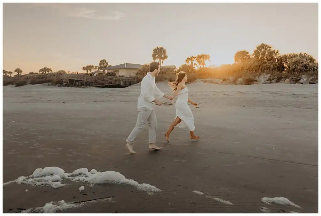 Engagement Portraits: the couple running along the wet sand at sunset, during their engagement session on Jekyll Island, GA