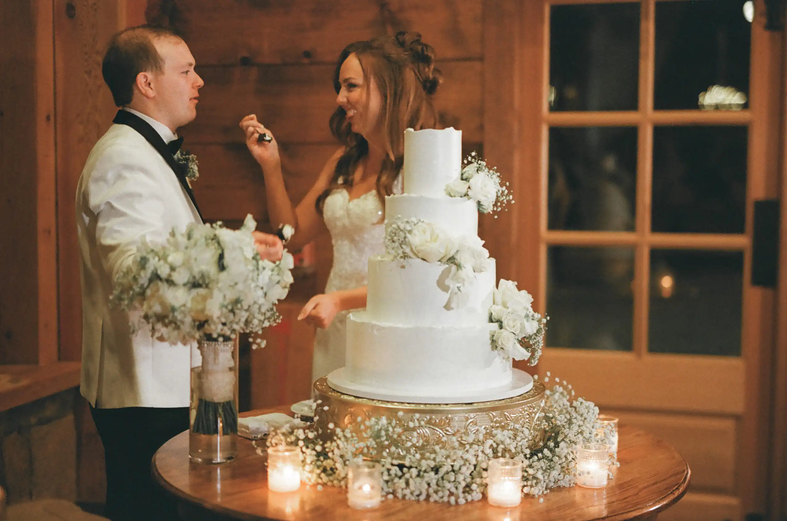 Bride and groom cutting their four-tier wedding cake by candlelight, shot on 35mm film