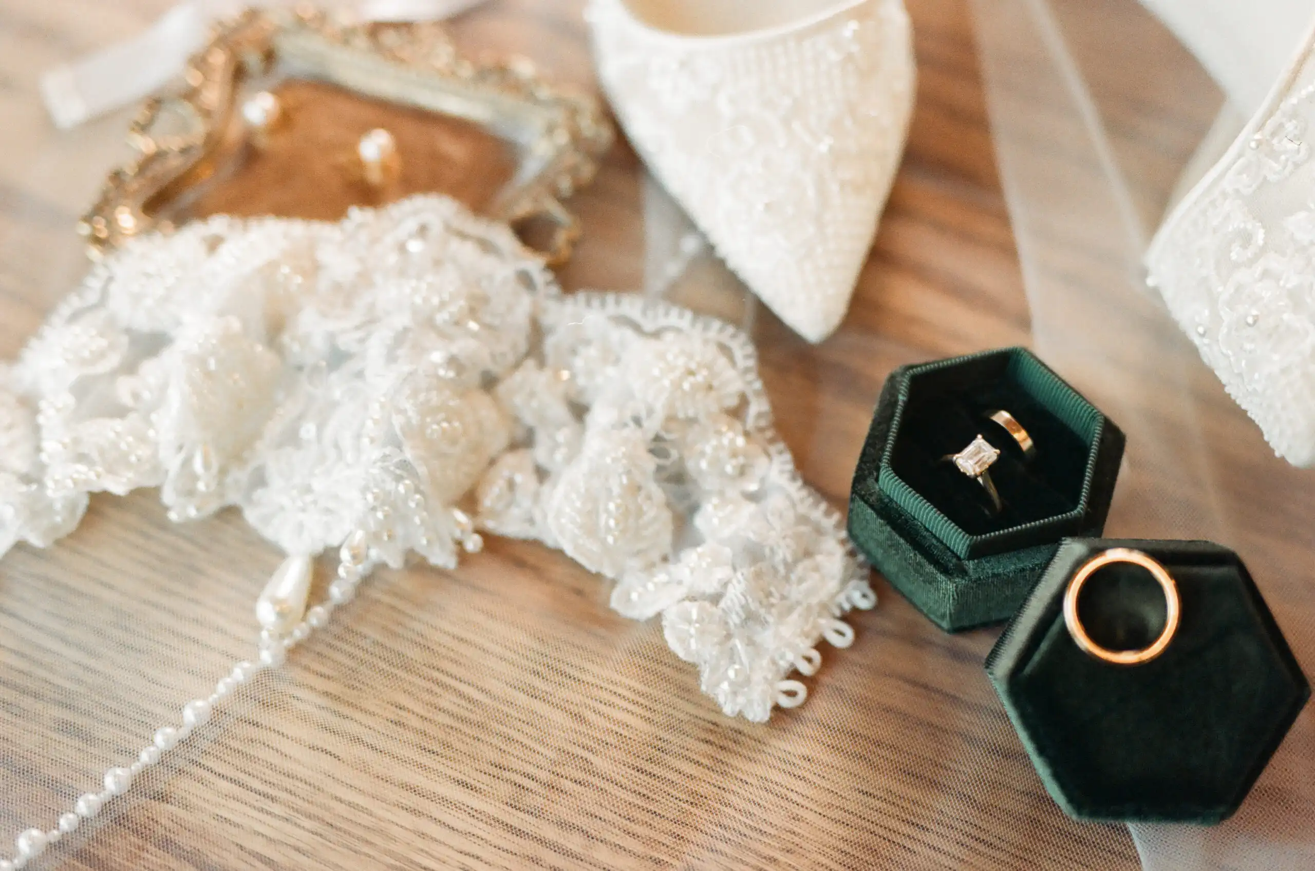 Beaded garter, bridal heels and the rings in green velvet boxes before a wedding, shot on 35mm film