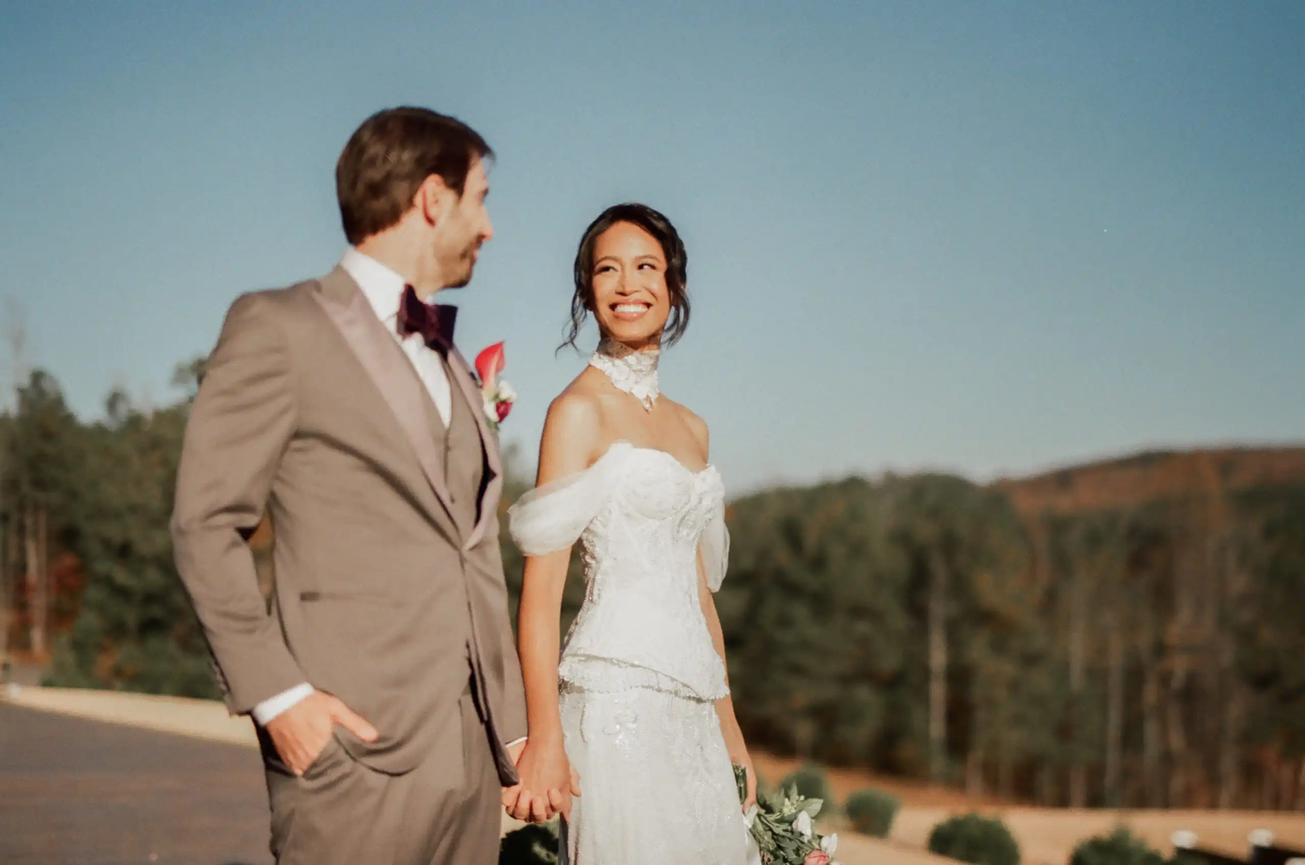 Groom in a taupe suit with the bride behind him at their wedding in the mountains, shot on 35mm film