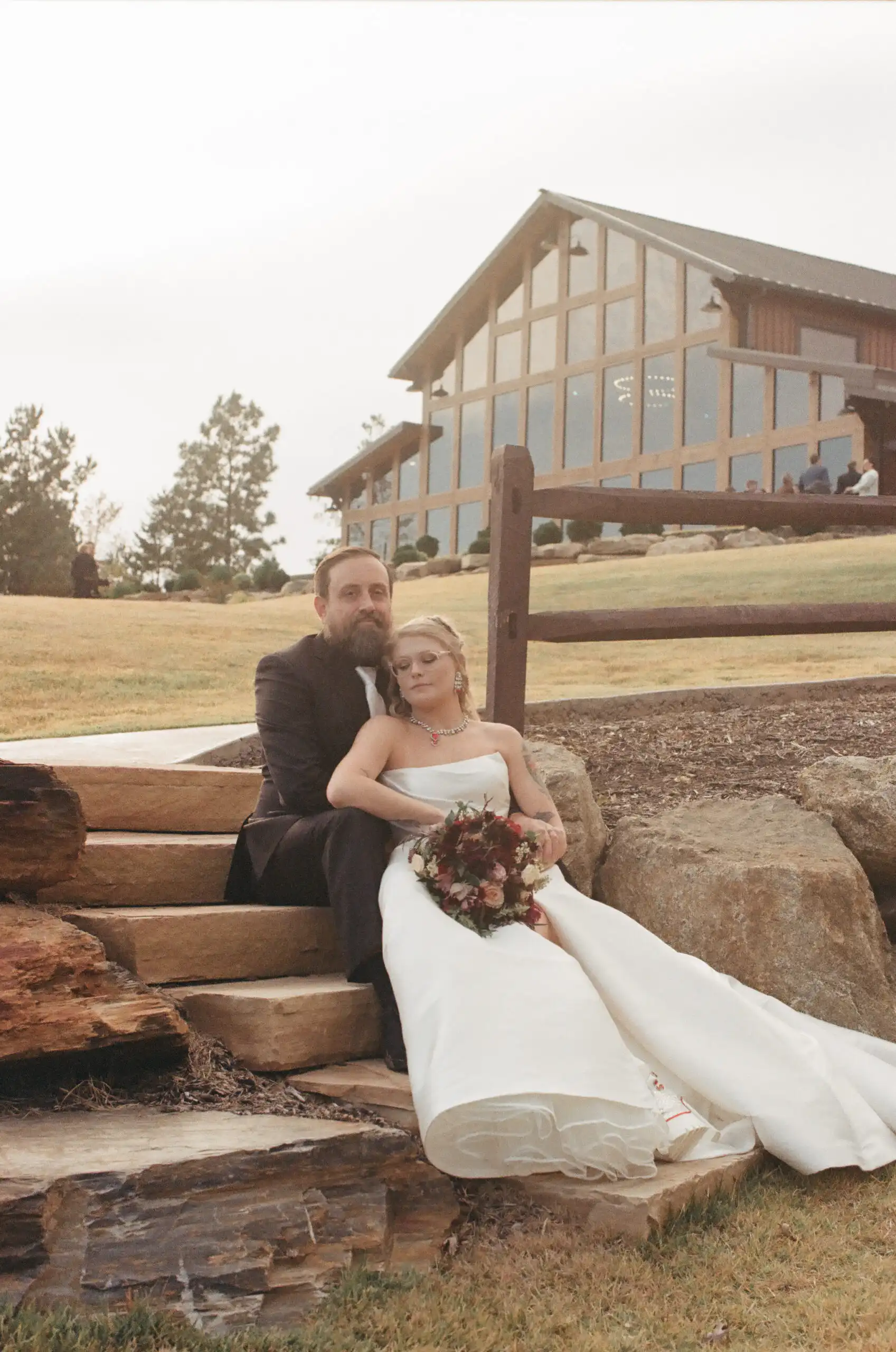 Bride and groom on the stone steps below the lodge at their wedding, shot on 35mm film at The Venue at Sharp Mountain in North Georgia