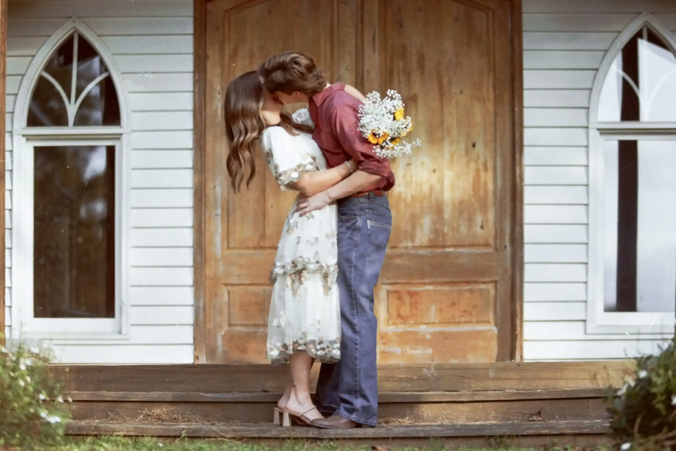 Couple kissing on the steps of an old white chapel, shot on 35mm film, in Canton, GA