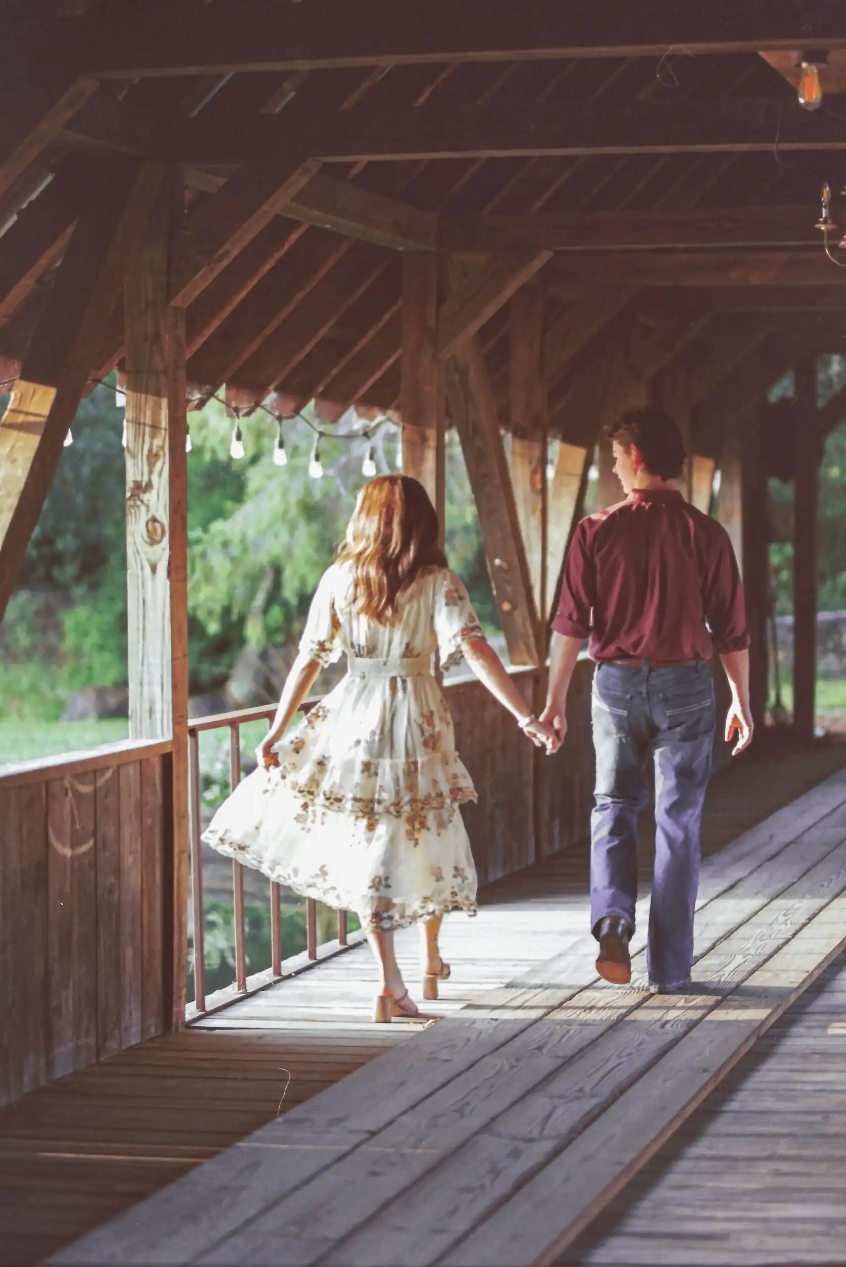 Couple walking hand in hand through a covered bridge, shot on 35mm film, in Canton, GA