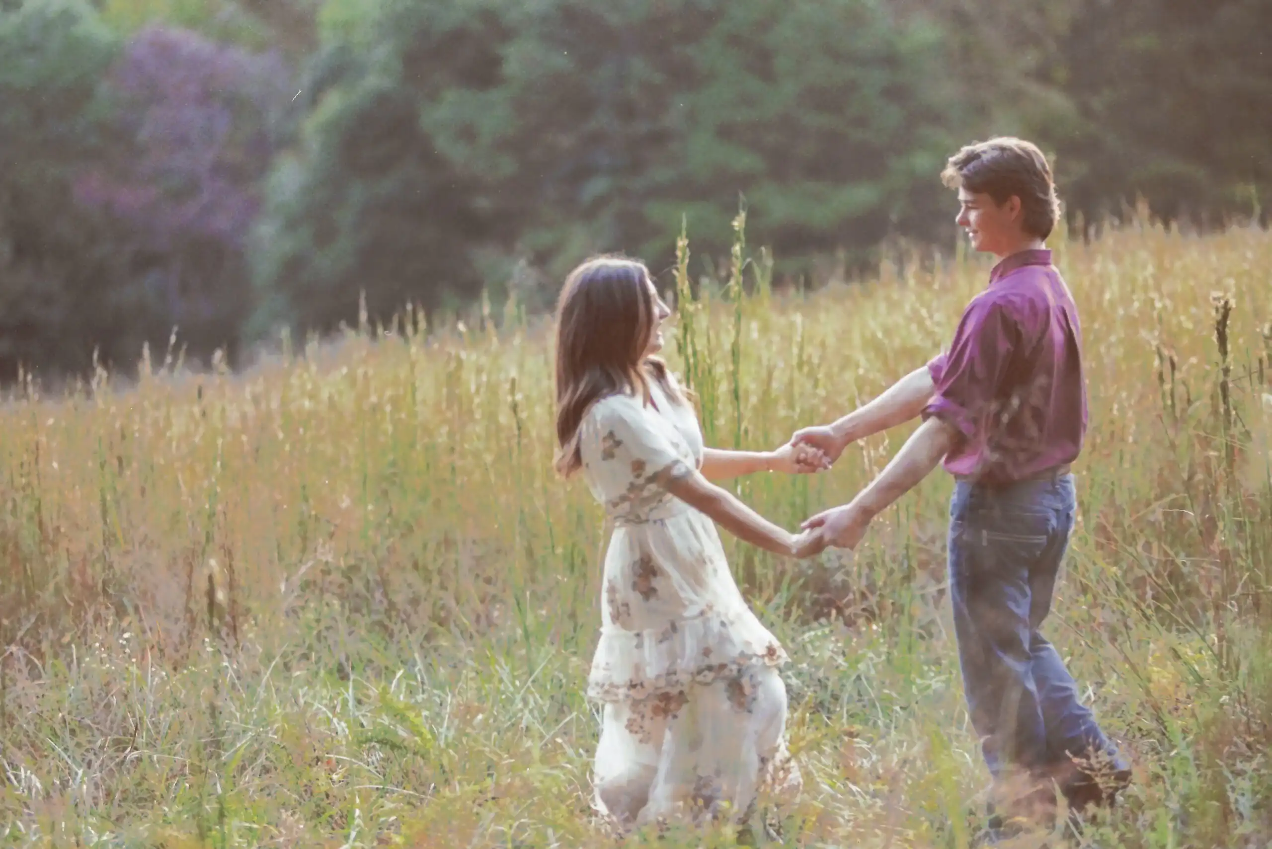 Couple holding hands in a tall-grass field at their engagement session, shot on 35mm film in Canton, GA