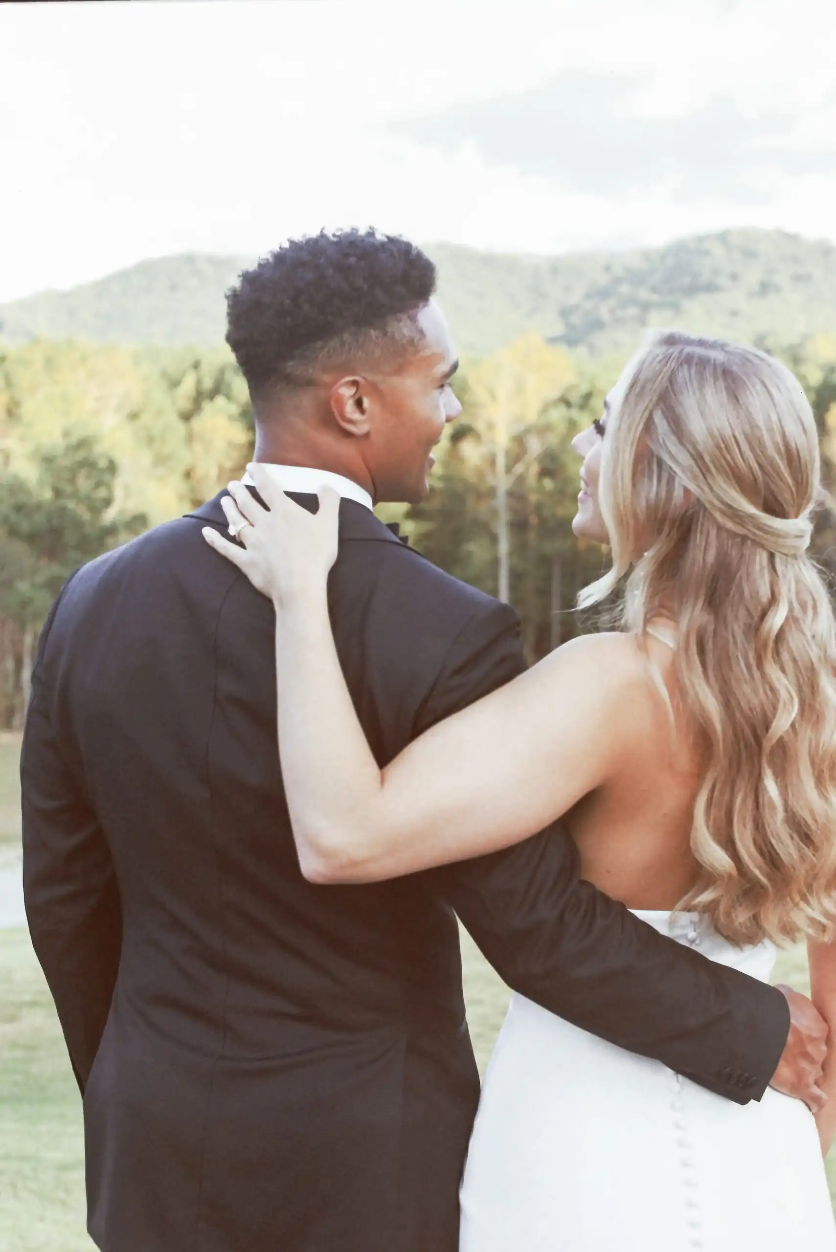 Bride's hand on the groom's shoulder with the mountains behind, shot on 35mm film