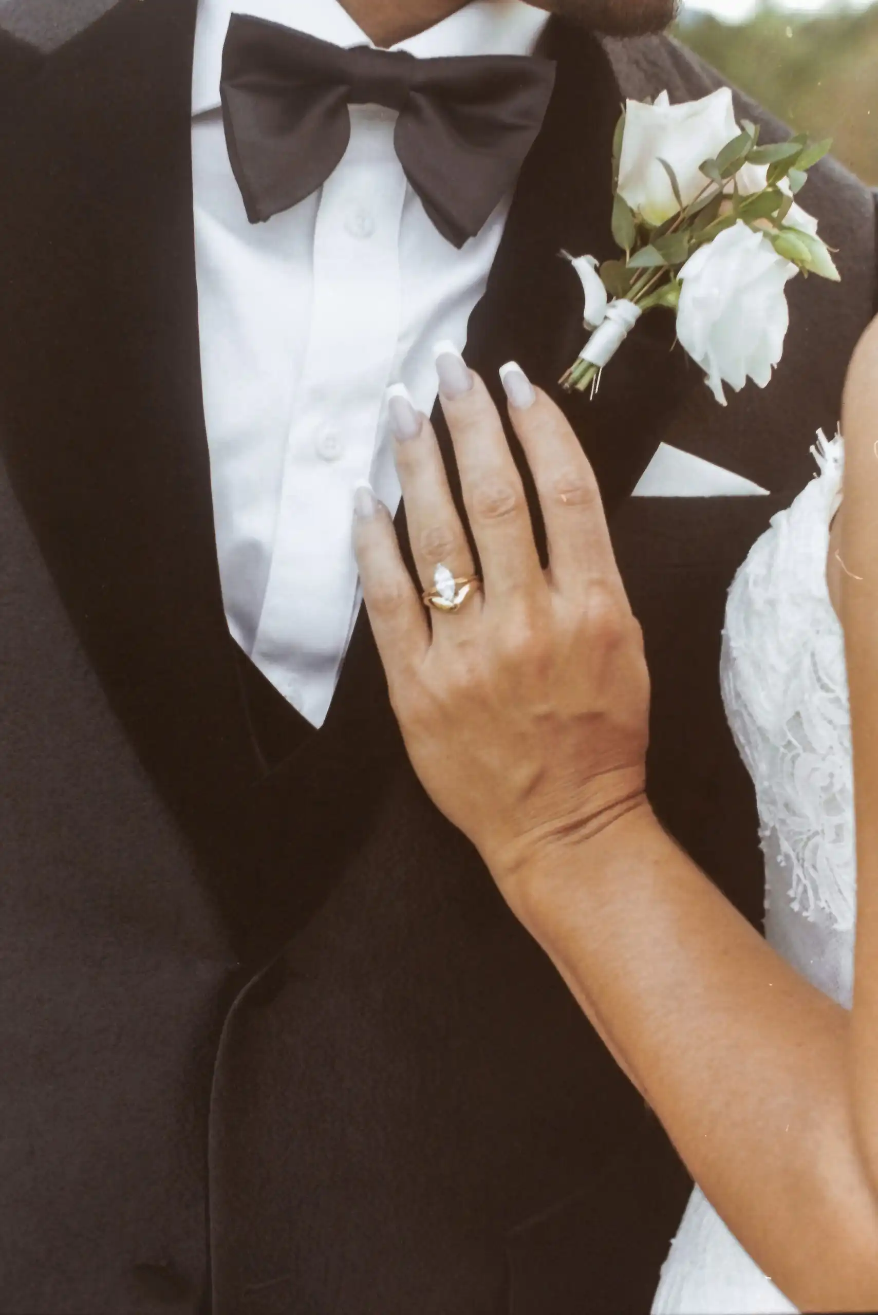 Bride's hand with her ring on the groom's lapel at their wedding, shot on 35mm film