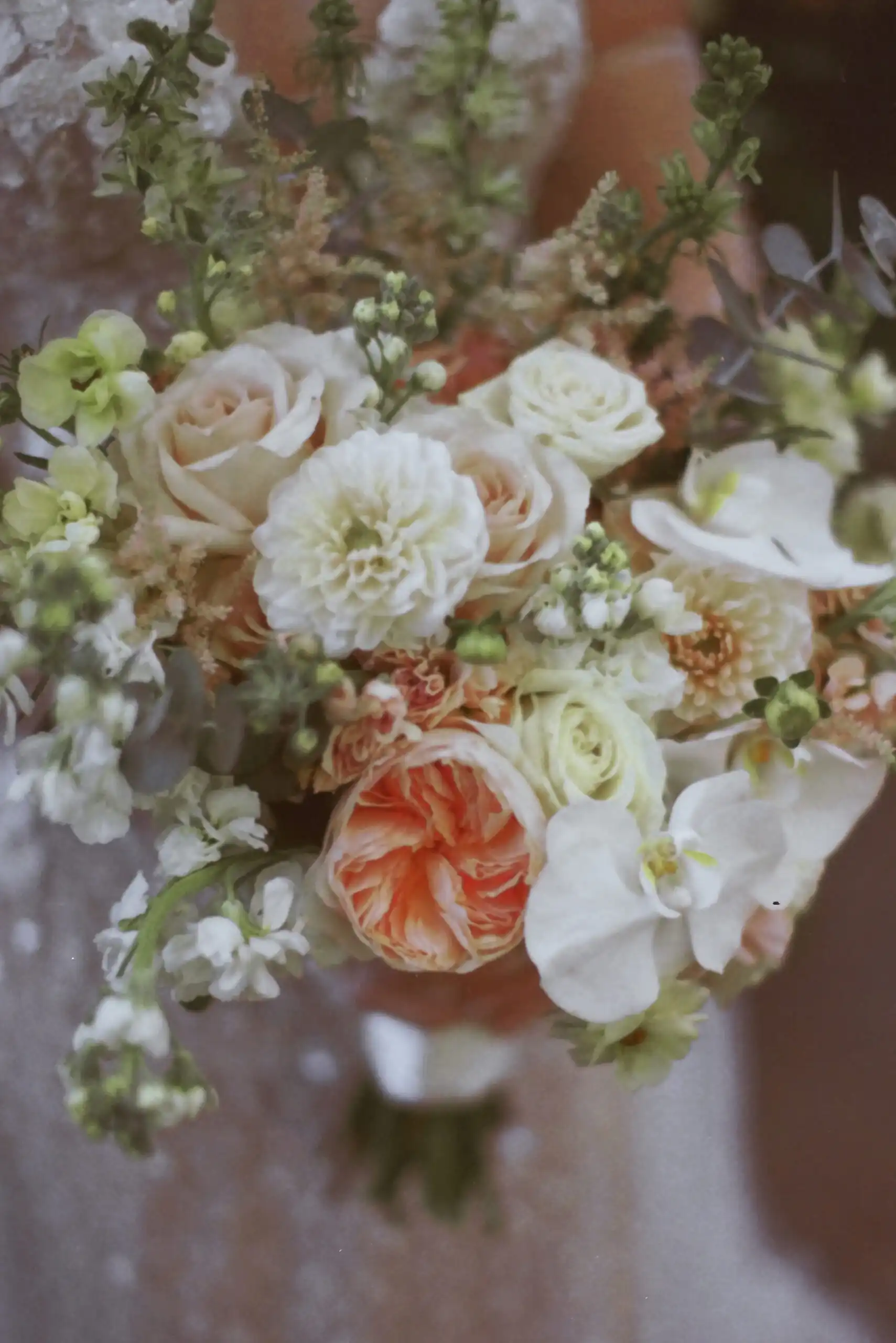 Bride's bouquet of peach roses and white orchids at her wedding, shot on 35mm film