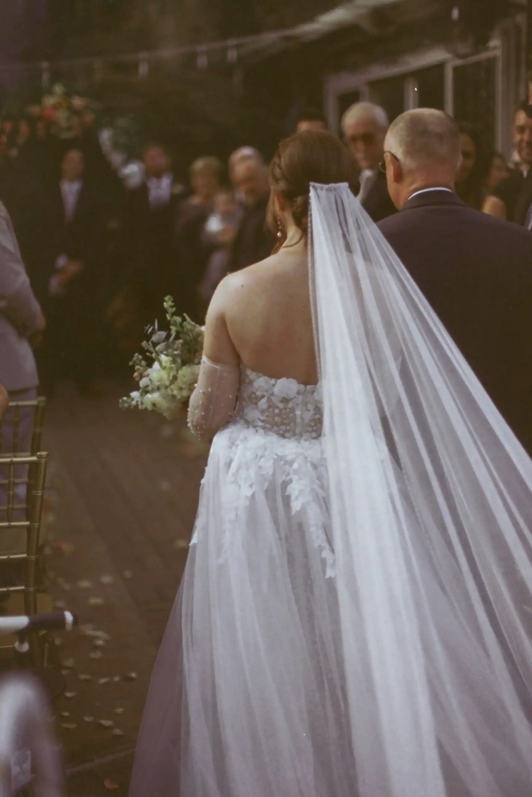 Bride walking down the aisle with a long veil at her wedding, shot on 35mm film at Wahoo! Grill in Decatur, GA