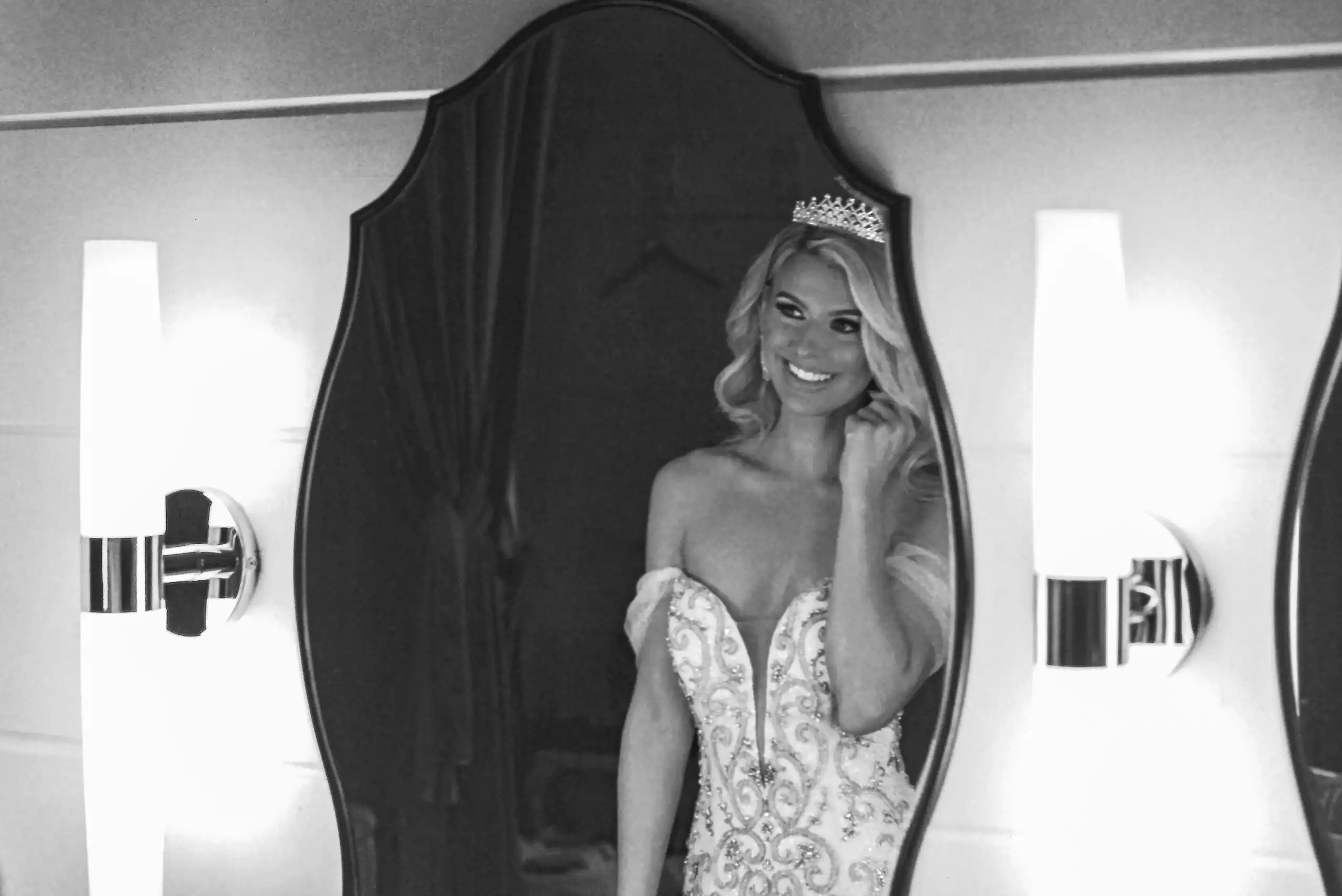 Bride in a tiara reflected in an ornate mirror before her wedding, in black and white on 35mm film