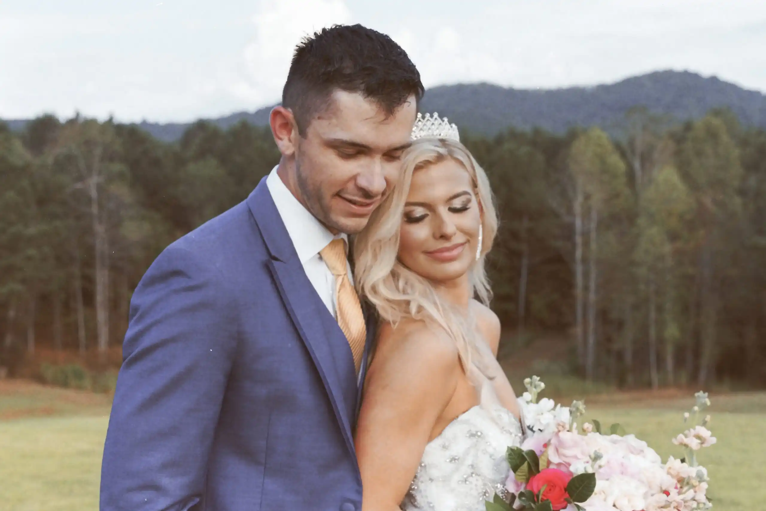 Bride in a tiara and the groom in a blue suit at their wedding in the mountains, shot on 35mm film