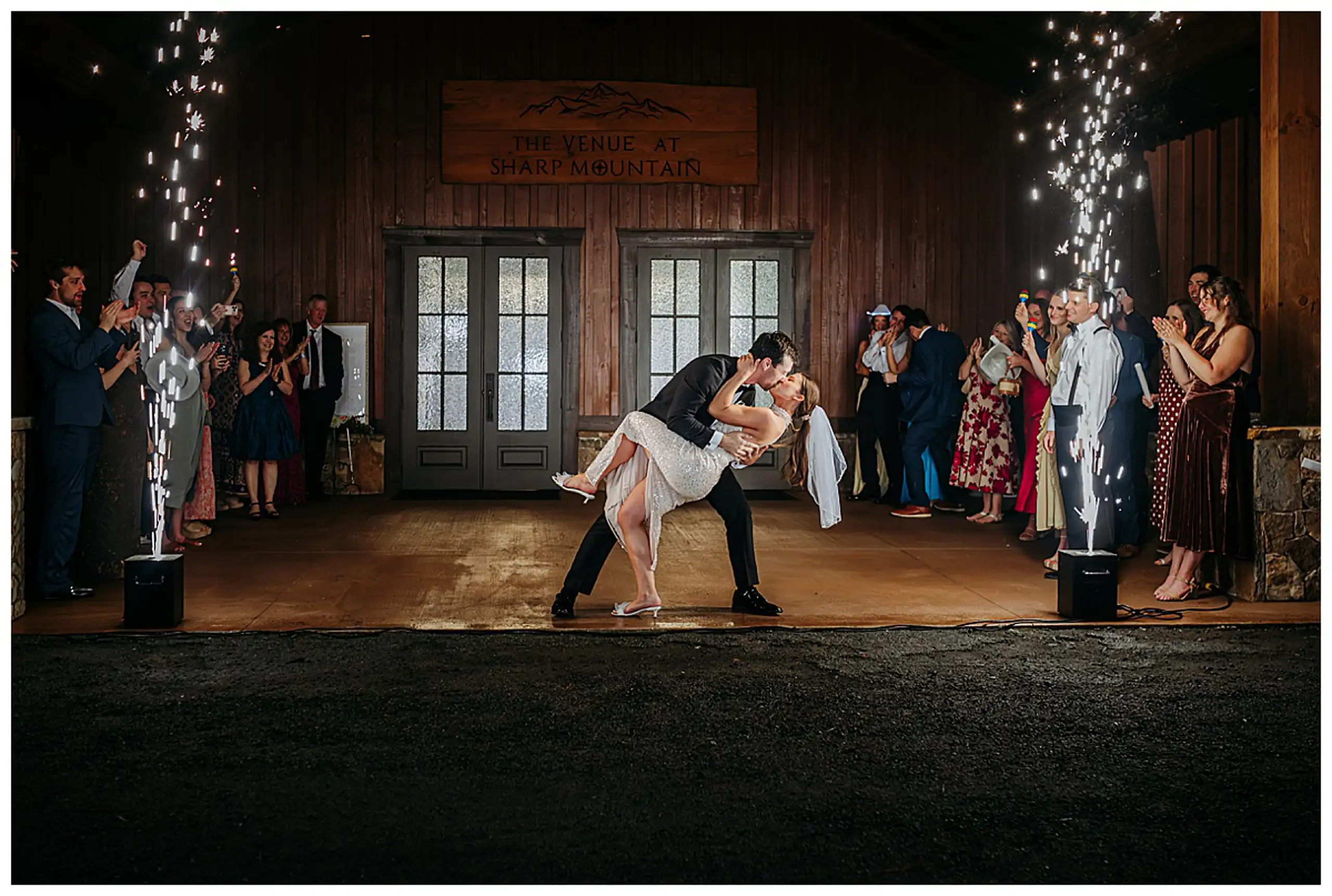 Send-Off: a dip kiss in the tunnel of cold sparks at the doors, at their wedding at The Venue at Sharp Mountain in Jasper, GA