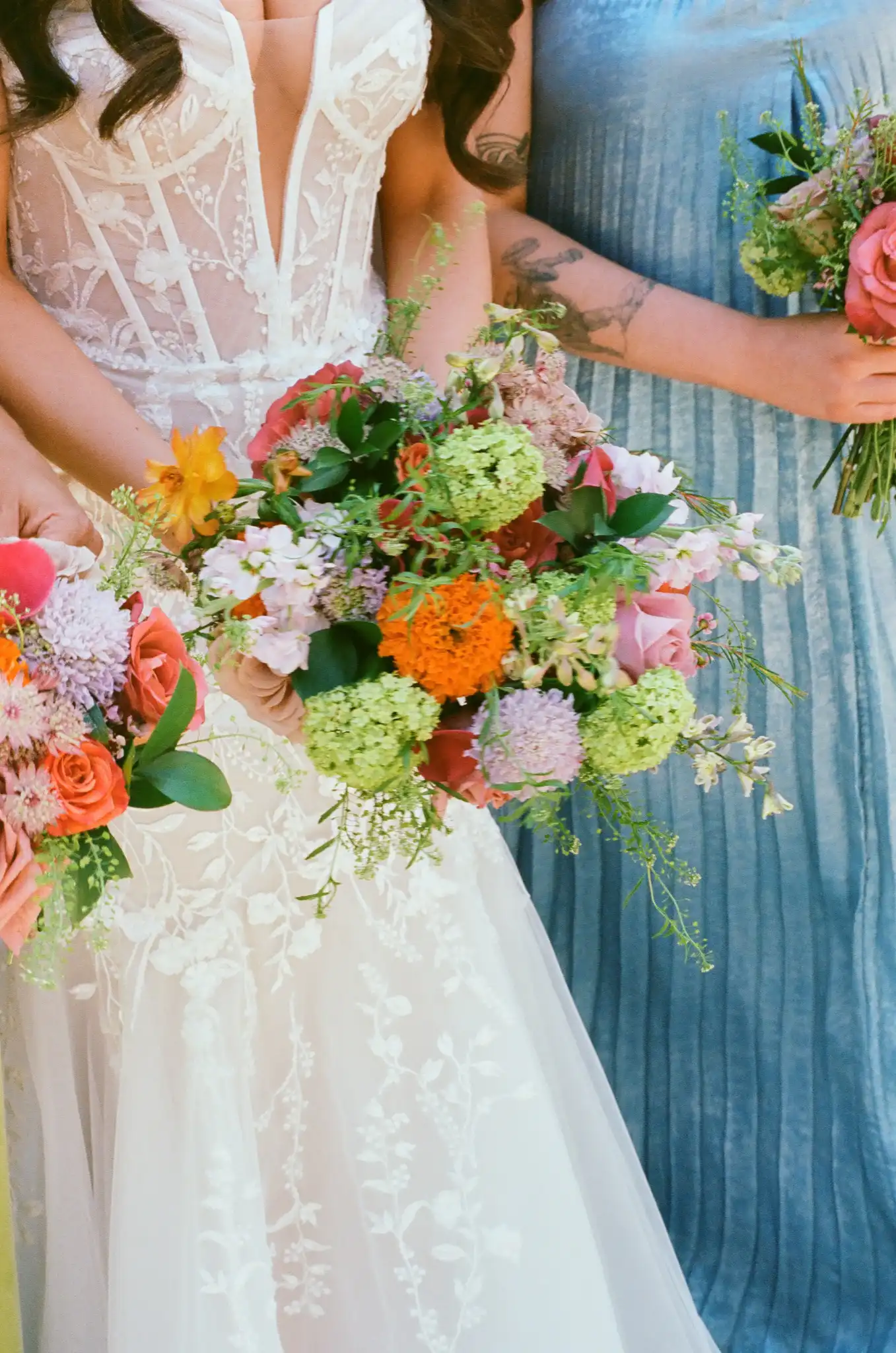 Bride's bouquet of zinnias, roses and garden greenery beside a bridesmaid in blue, shot on 35mm film at The Venue at Sharp Mountain in Jasper, Georgia