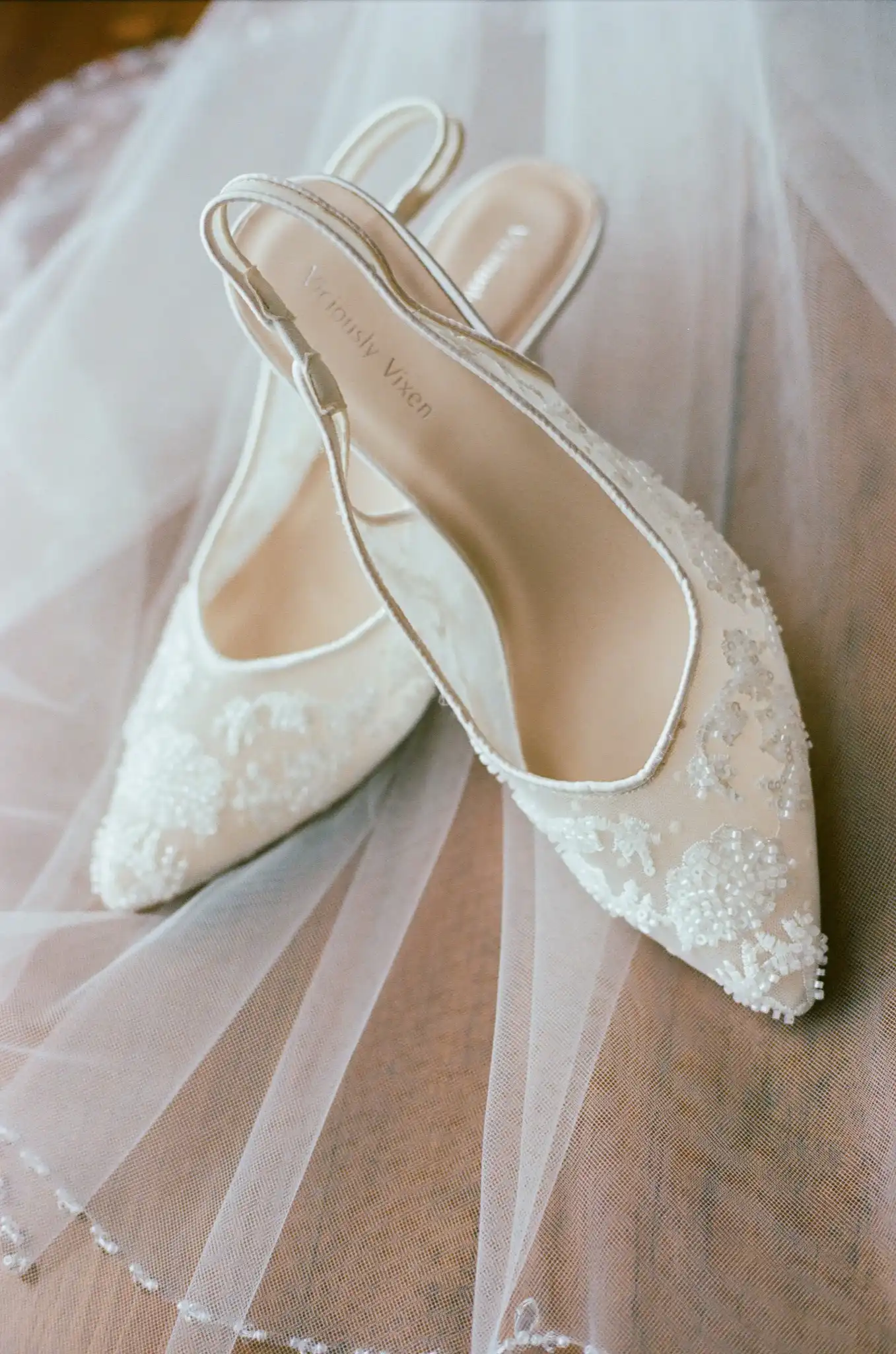 Beaded lace bridal heels resting on the veil before the wedding, shot on 35mm film at The Venue at Sharp Mountain in Jasper, Georgia