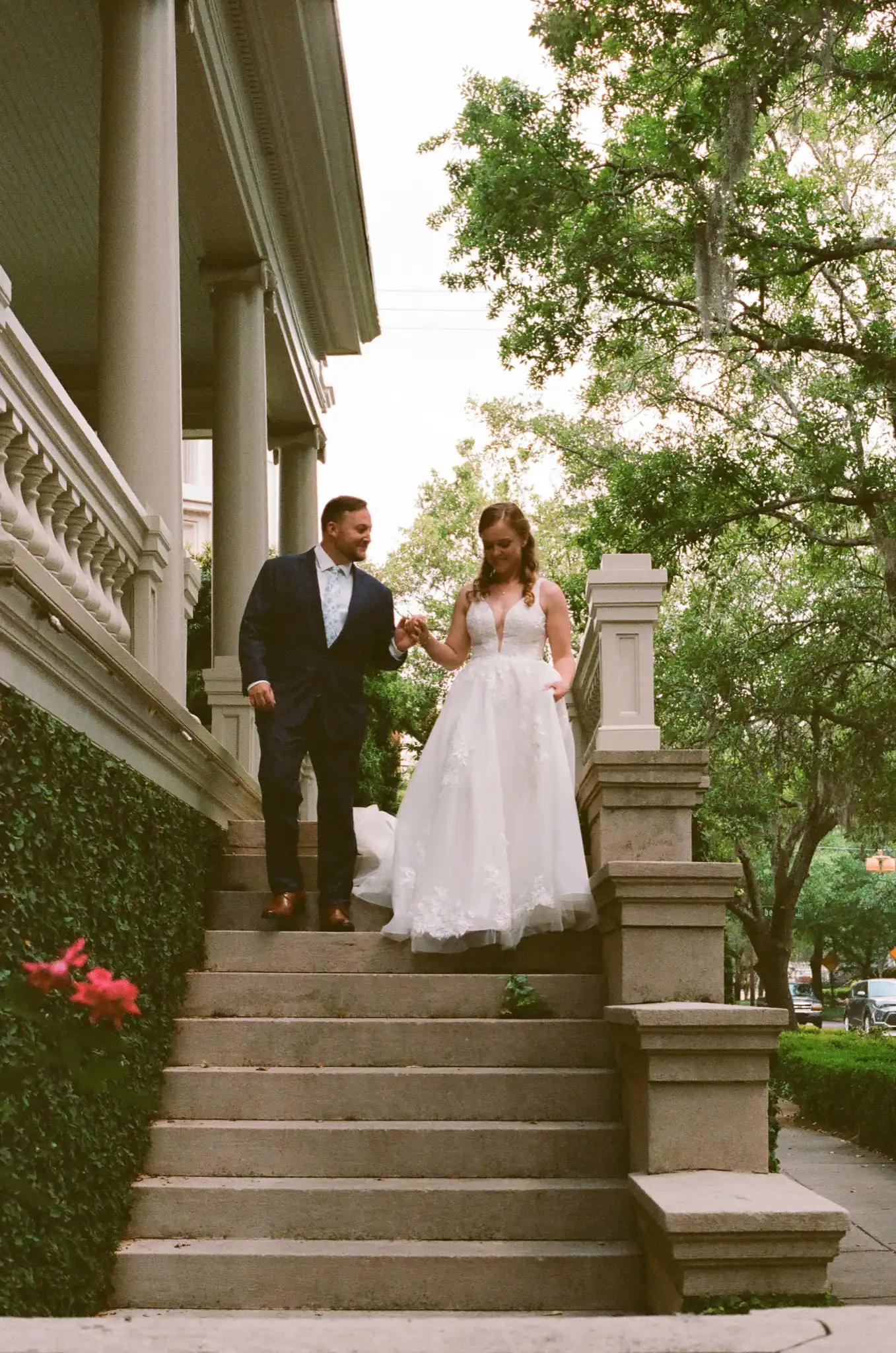 Bride and groom walking down the front steps of a historic home, shot on 35mm film in Savannah, Georgia