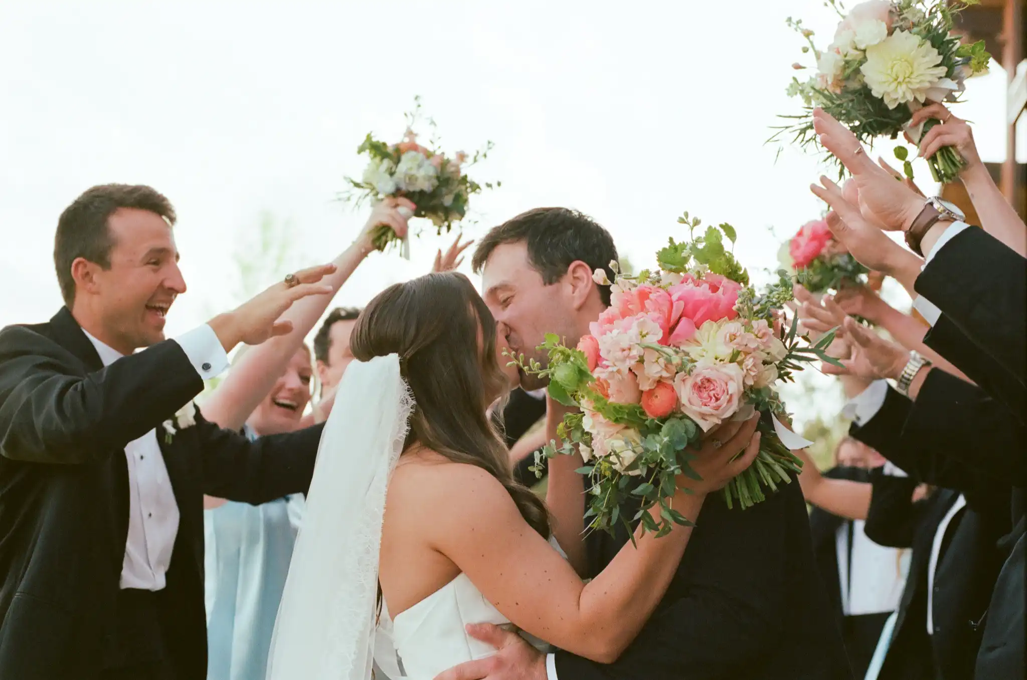 Bride and groom kissing as the wedding party cheers around them, shot on 35mm film at The Venue at Sharp Mountain in Jasper, Georgia