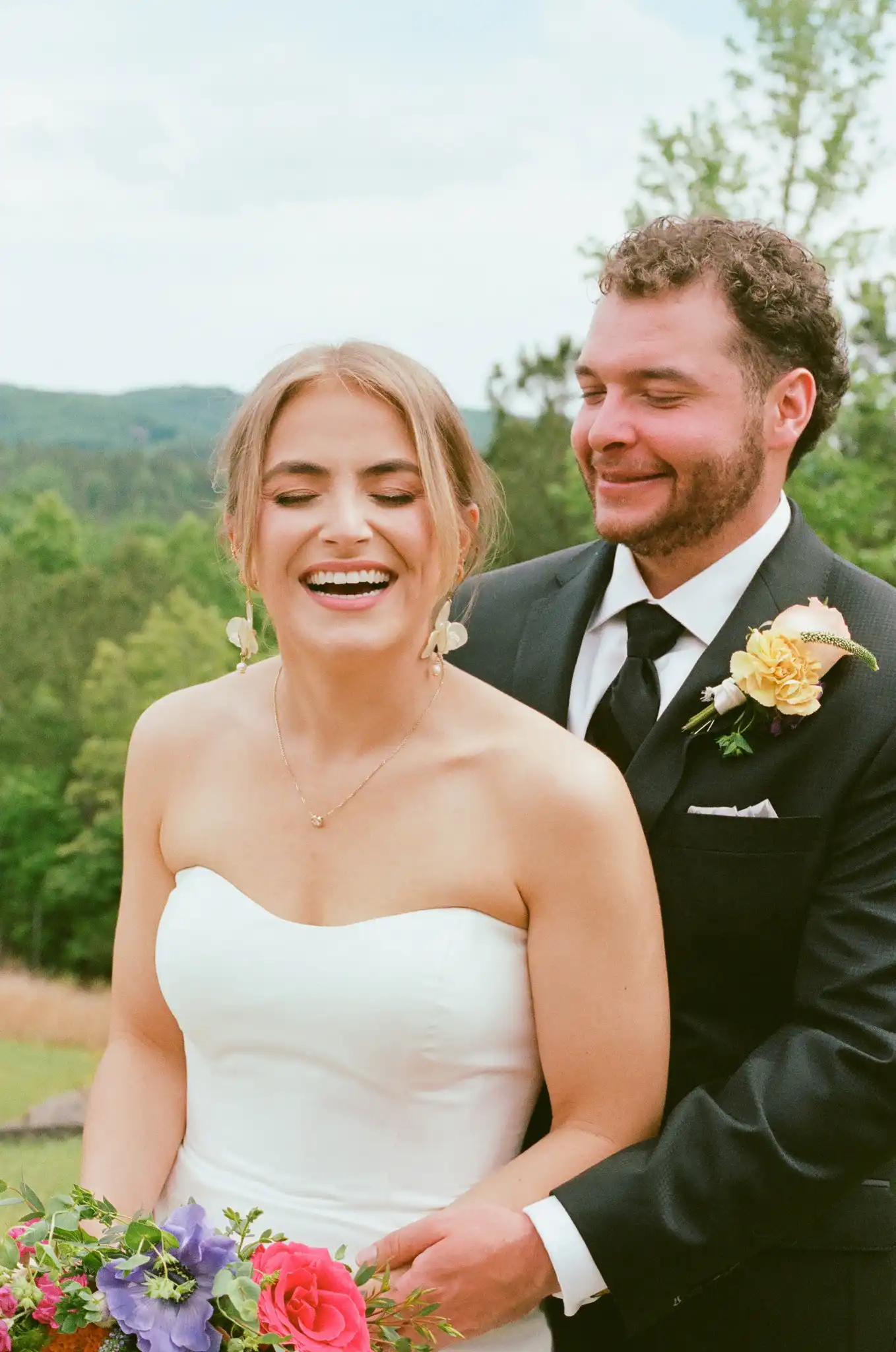 Bride laughing with the groom behind her and the mountains beyond, shot on 35mm film at The Venue at Sharp Mountain in Jasper, Georgia