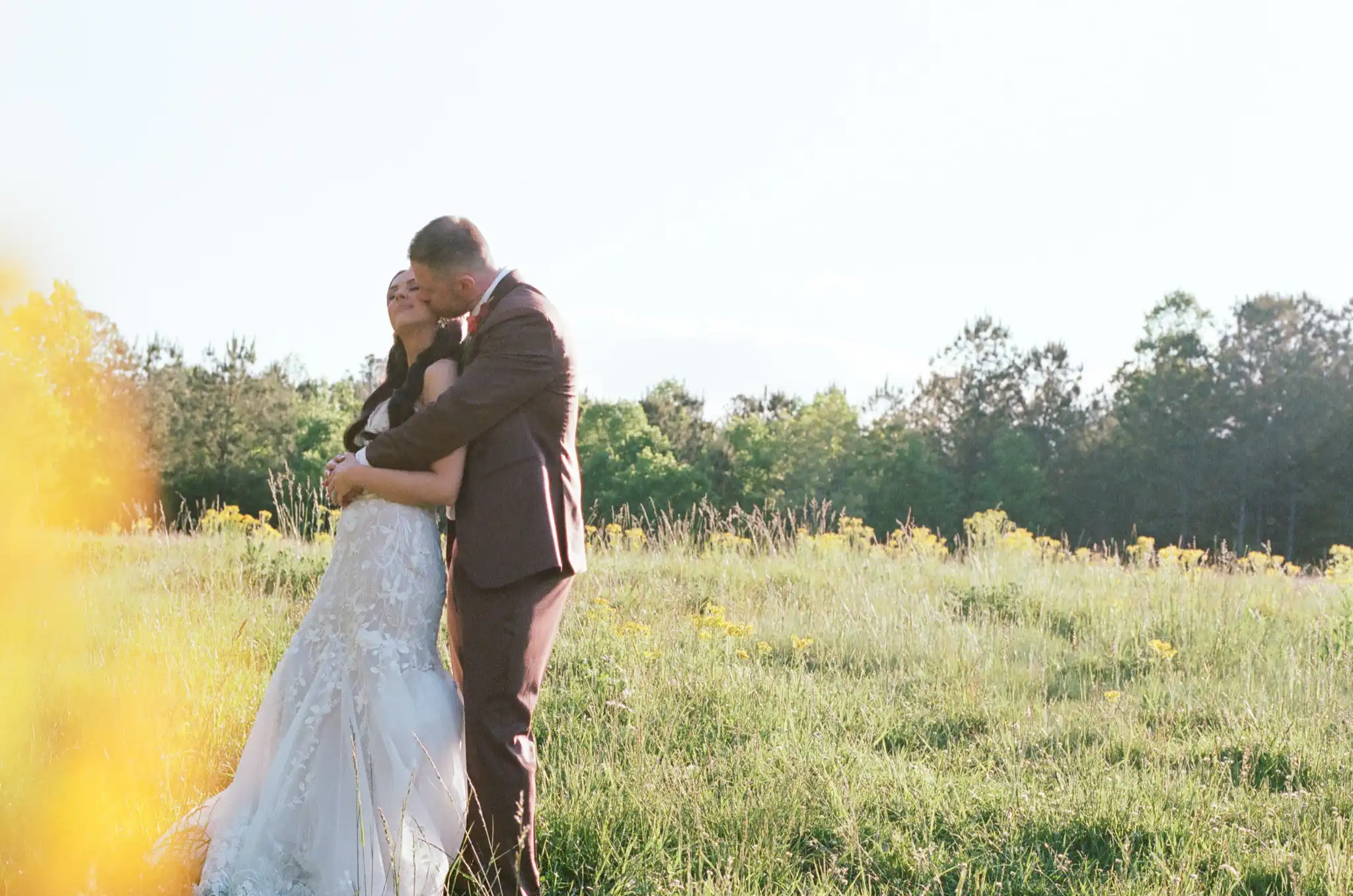 Bride and groom embracing in a wildflower field at golden hour, shot on 35mm film at The Venue at Sharp Mountain in Jasper, Georgia