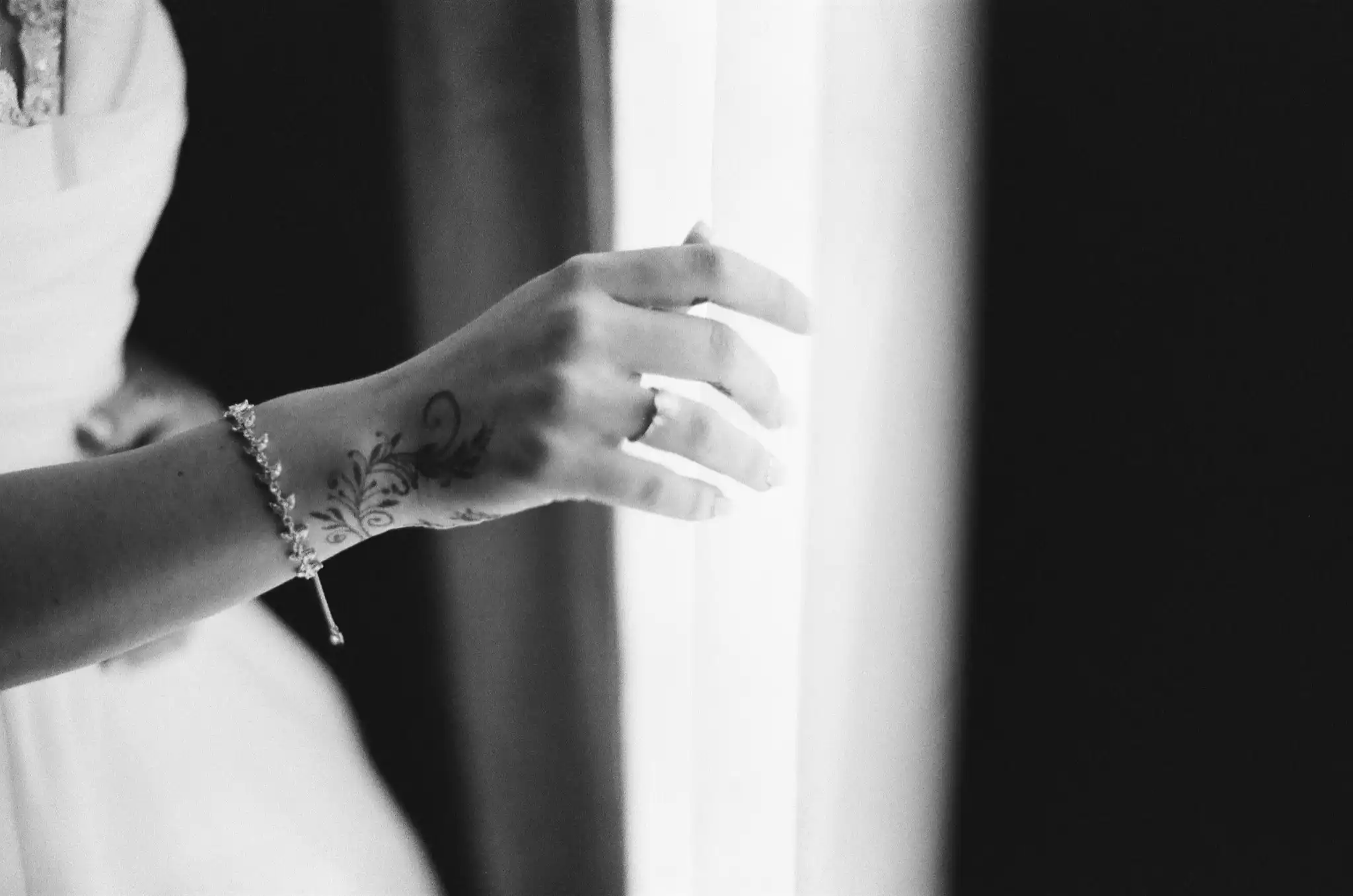 Bride's henna-decorated hand at the curtain before her wedding, in black and white on 35mm film at The Venue at Sharp Mountain in Jasper, Georgia