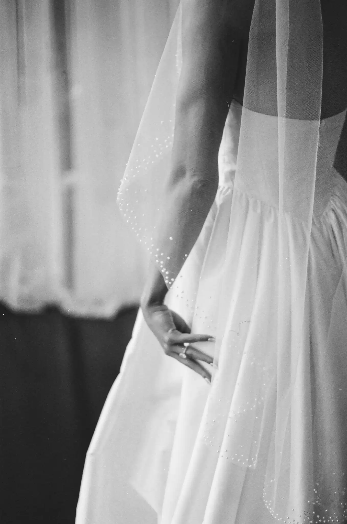 Bride's hand at her waist beneath a pearl-dotted veil, in black and white on 35mm film at The Venue at Sharp Mountain in Jasper, Georgia