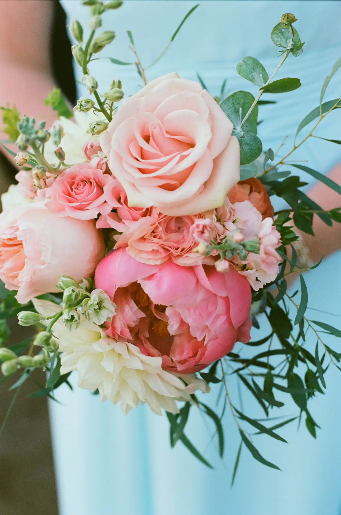 Bridesmaid's bouquet of pink peonies and roses against a blue dress, shot on 35mm film at The Venue at Sharp Mountain in Jasper, Georgia