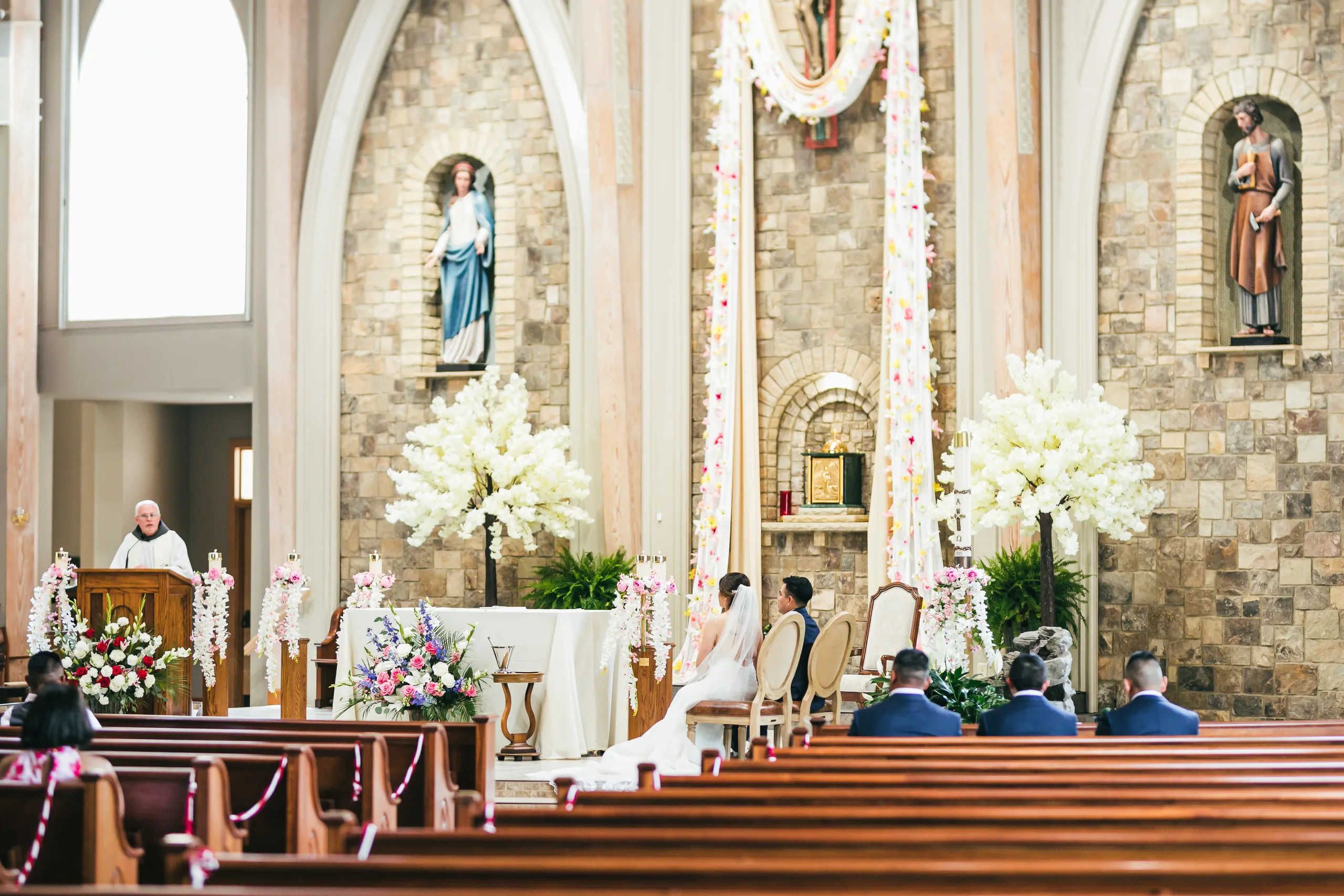 Wedding Ceremony: the couple seated at the altar during Mass at their wedding at Holy Cross Catholic Church in Atlanta, GA