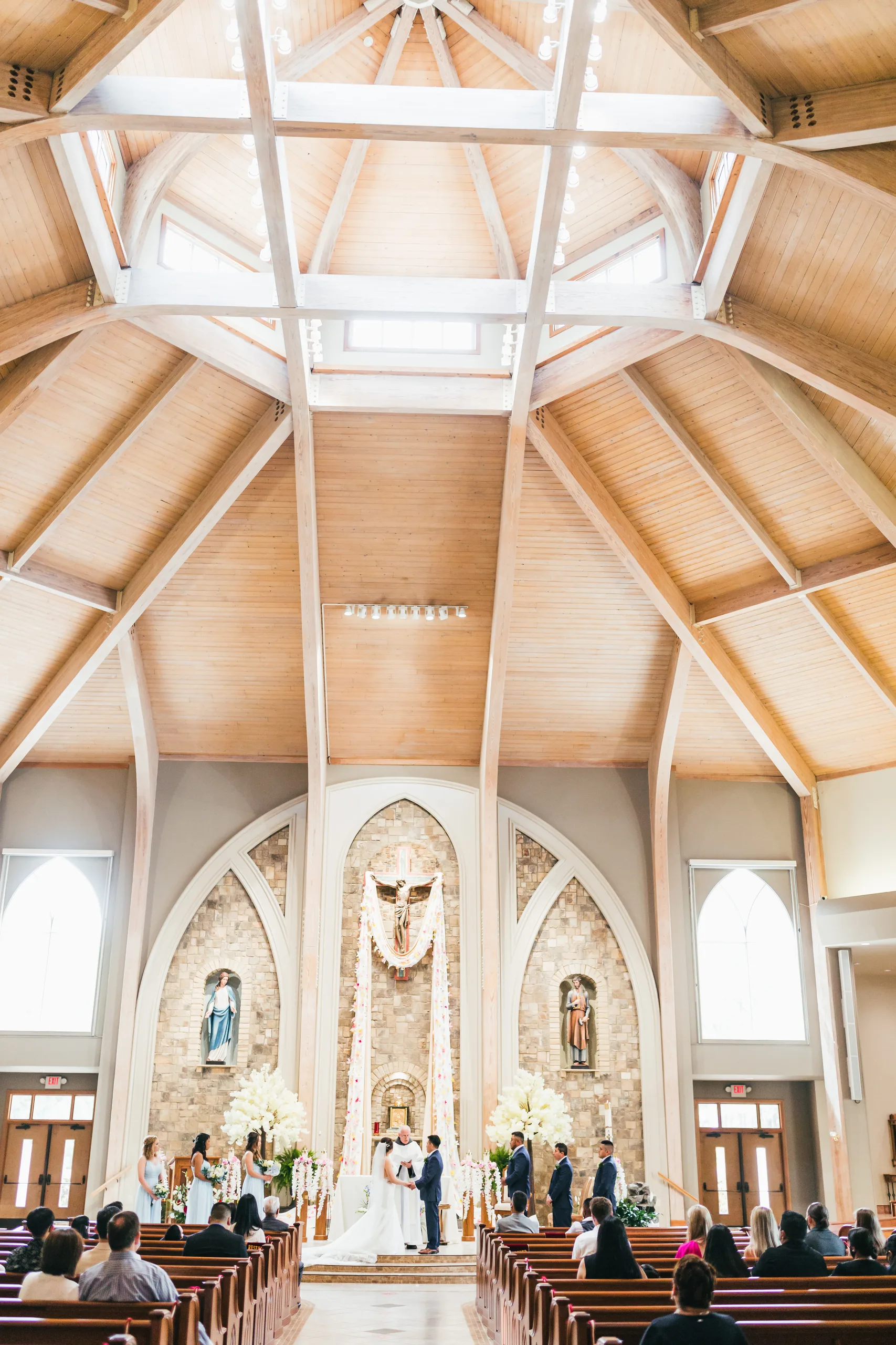 Wedding Ceremony: the church from the back under the wood beam ceiling at their wedding at Holy Cross Catholic Church in Atlanta, GA