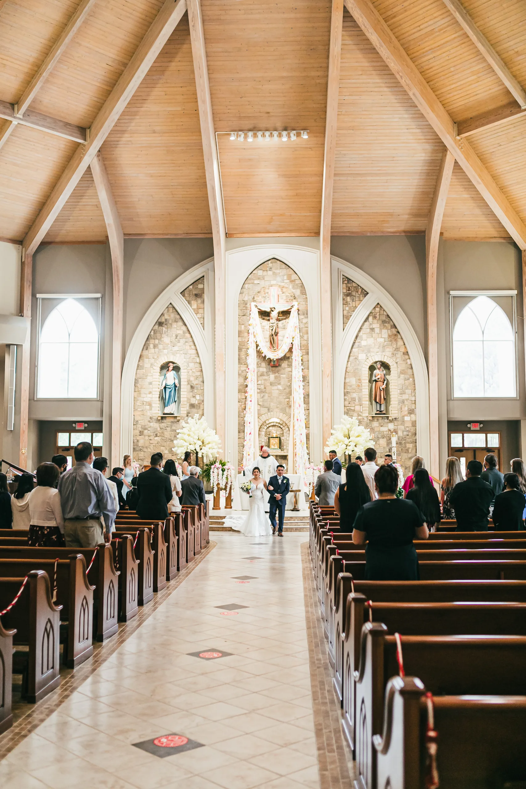 Wedding Ceremony: the ceremony seen from the aisle at their wedding at Holy Cross Catholic Church in Atlanta, GA