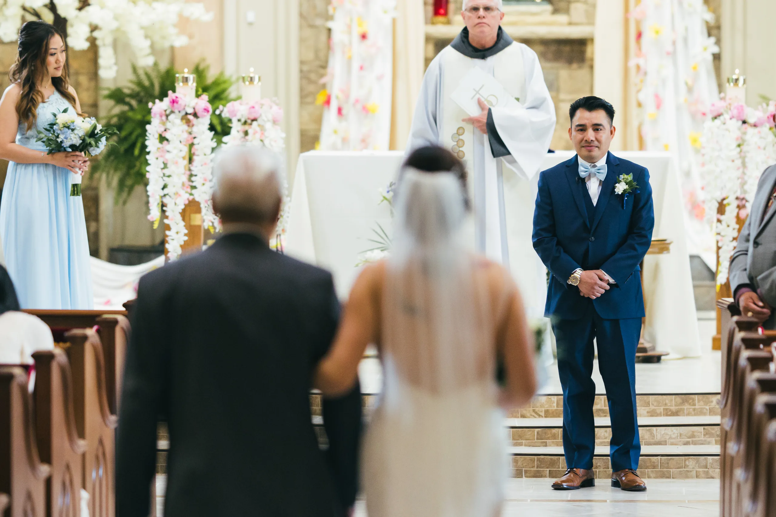 Wedding Ceremony: the groom waiting at the altar as she walks up the aisle at their wedding at Holy Cross Catholic Church in Atlanta, GA