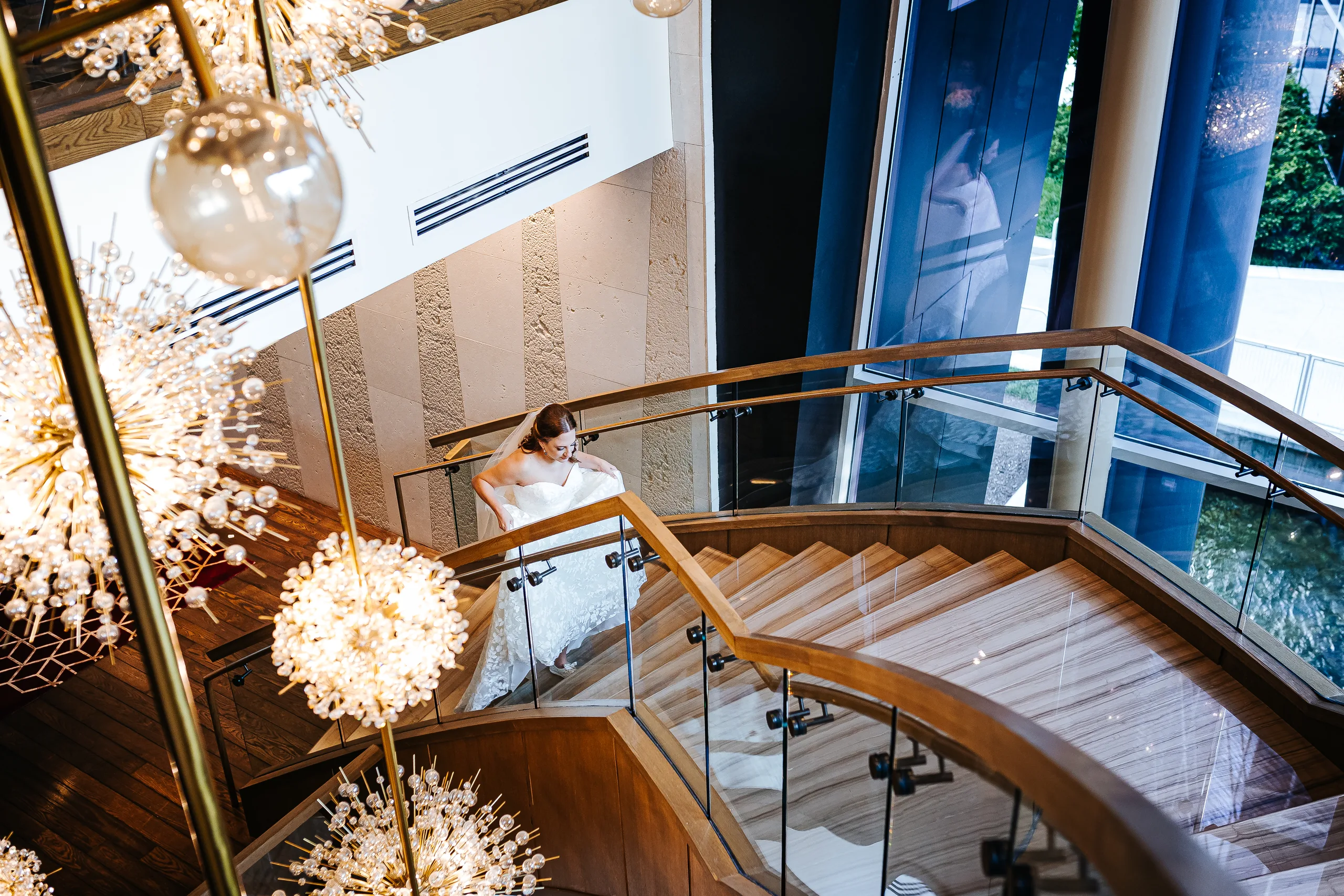 Bridal Portraits: the bride on the staircase from above with the chandeliers at their wedding at the Omni Hotel at The Battery in Atlanta, GA