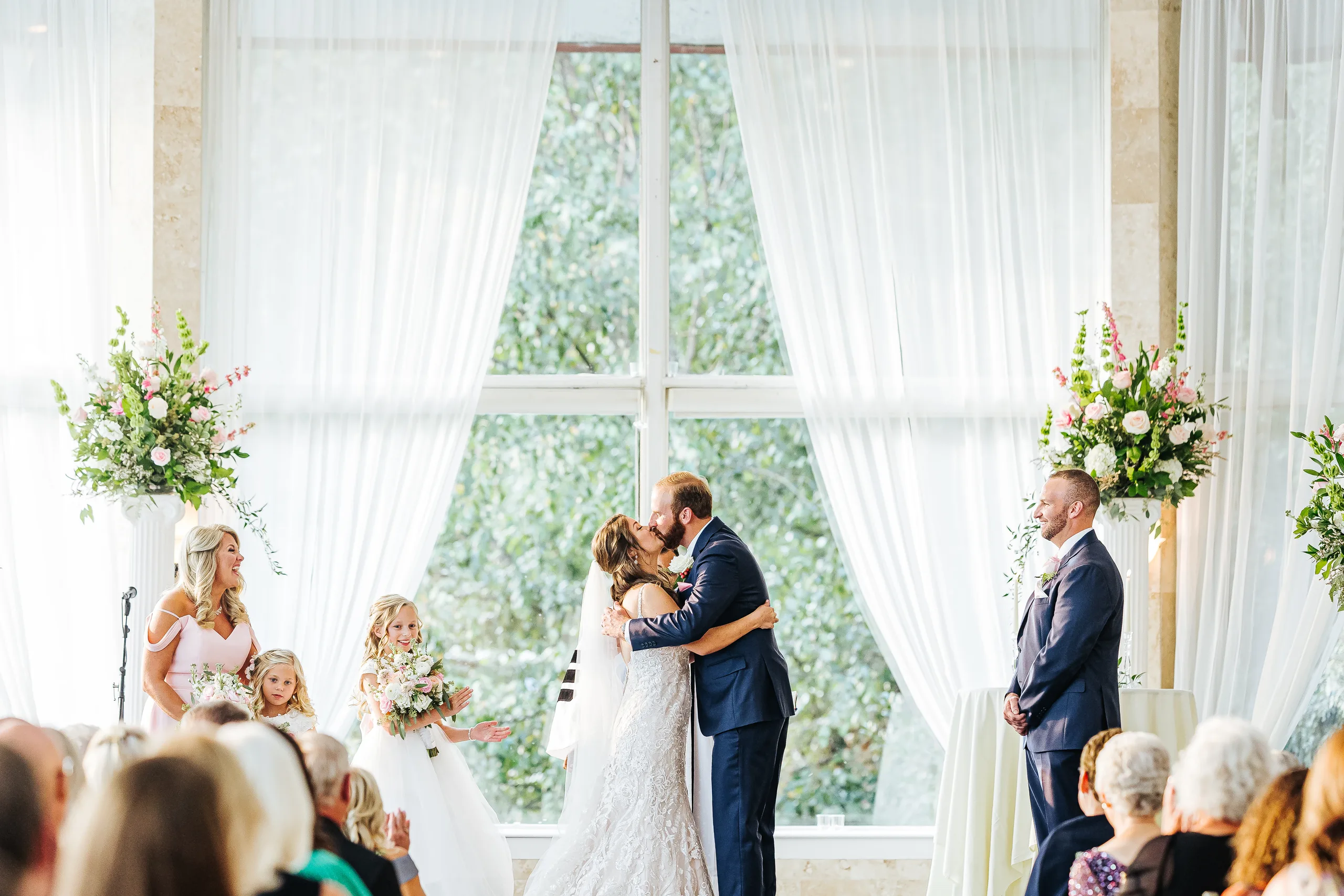 Wedding Ceremony: the first kiss in front of the tall windows, at their wedding at The Piedmont Room in Atlanta, GA