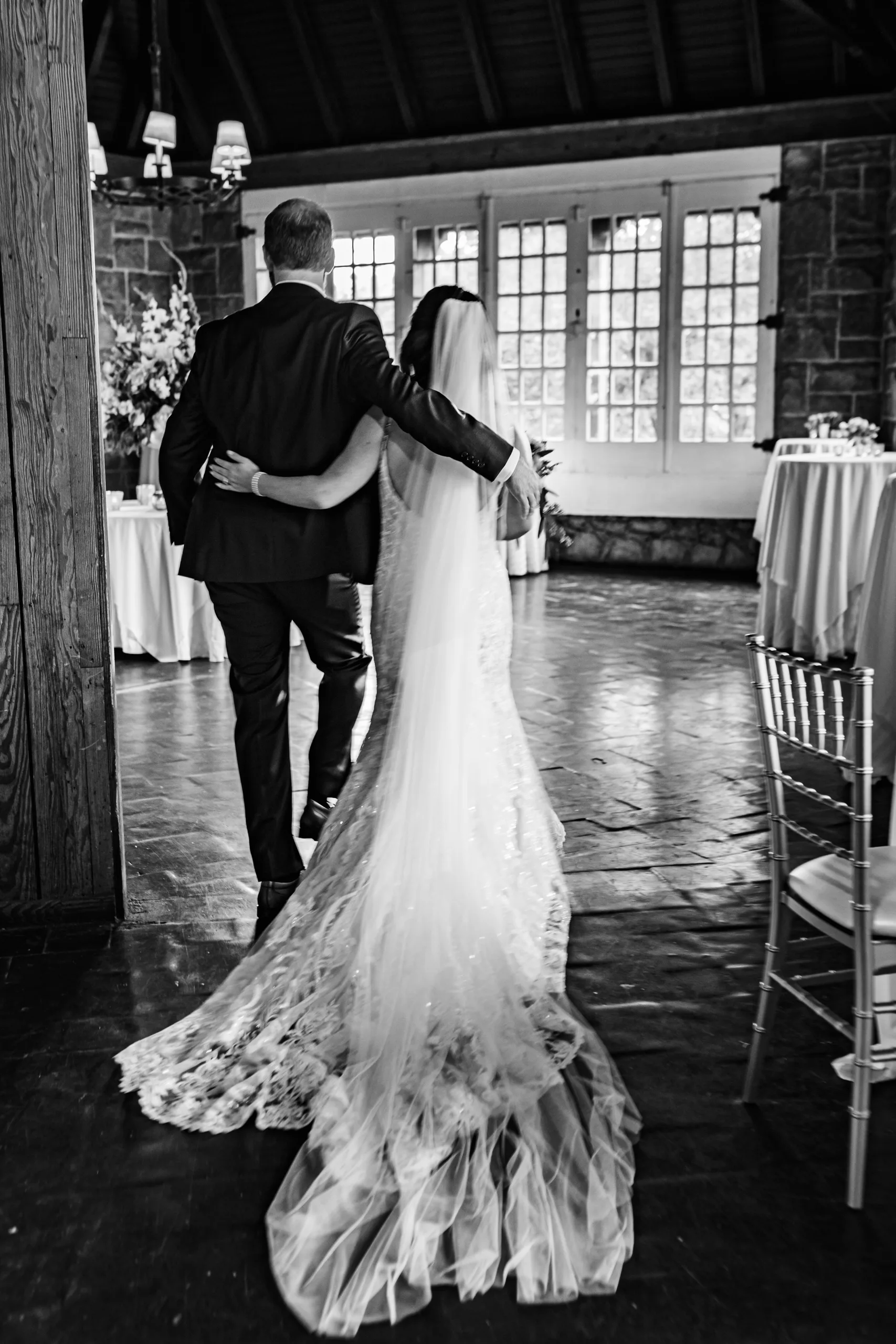 Wedding Ceremony: the bride and her dad walking in arm in arm, in black and white, at their wedding at The Piedmont Room in Atlanta, GA