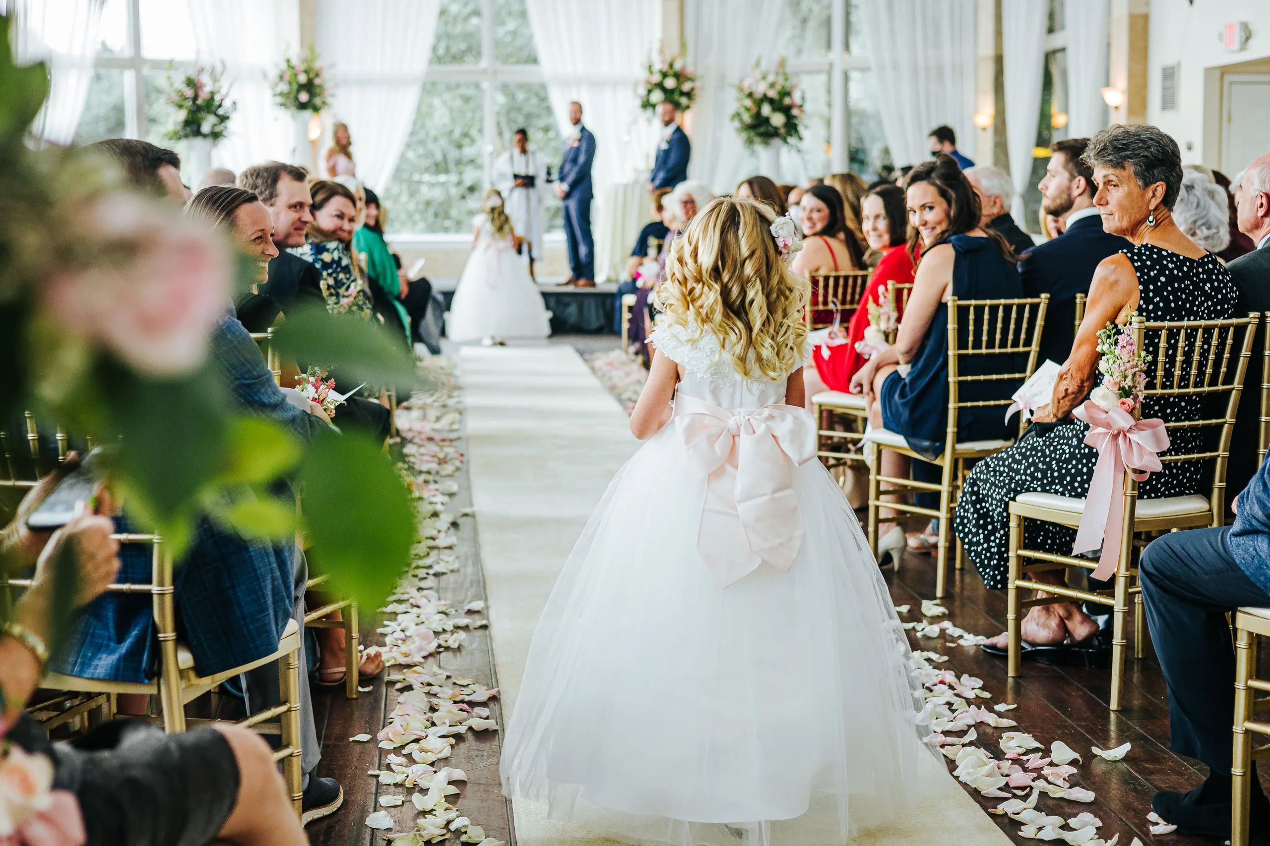 Wedding Ceremony: a flower girl walking down the aisle, at their wedding at The Piedmont Room in Atlanta, GA