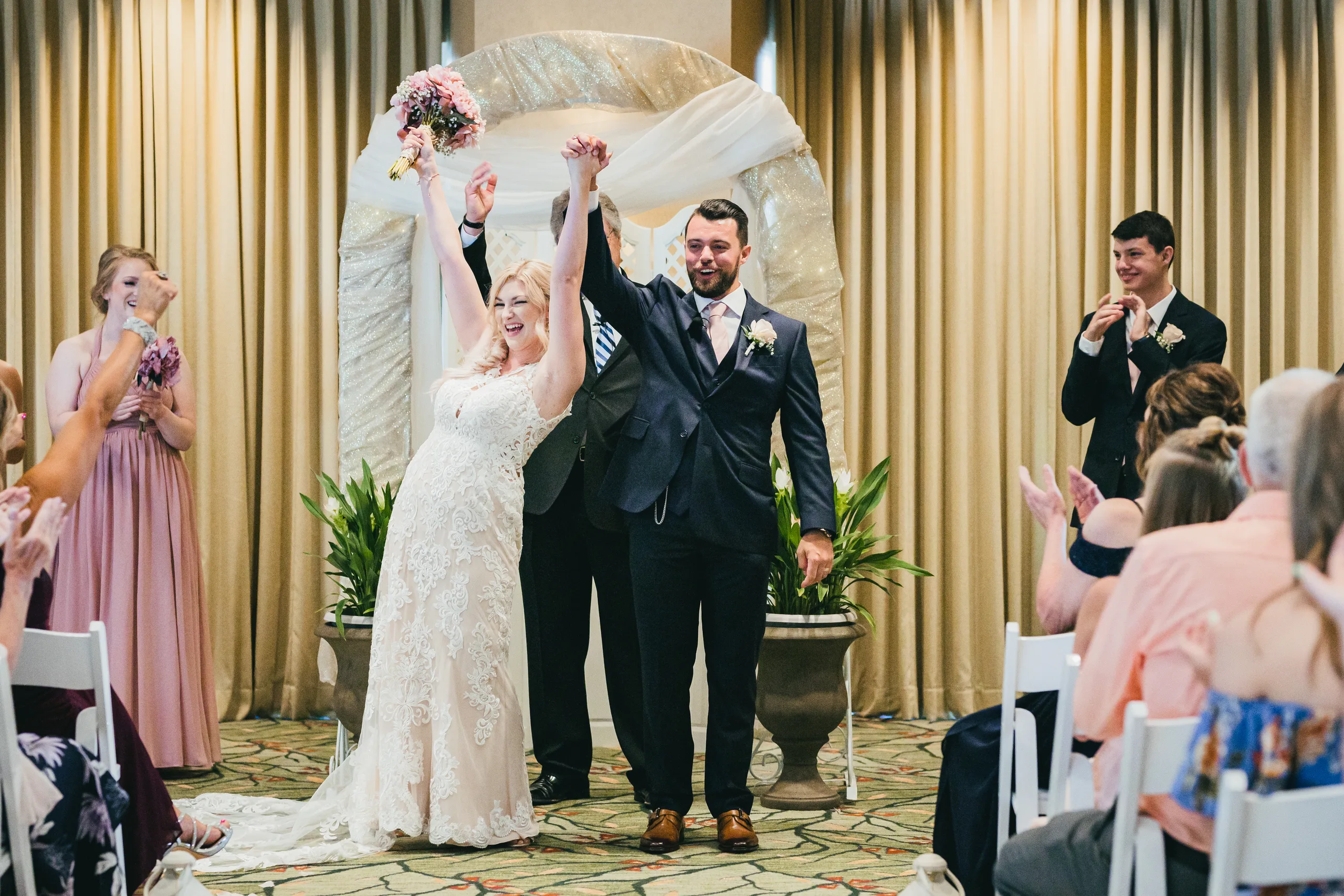 Wedding Ceremony: their arms raised as they walk back up the aisle, at their wedding at Atlanta Evergreen Lakeside Resort in Stone Mountain, GA