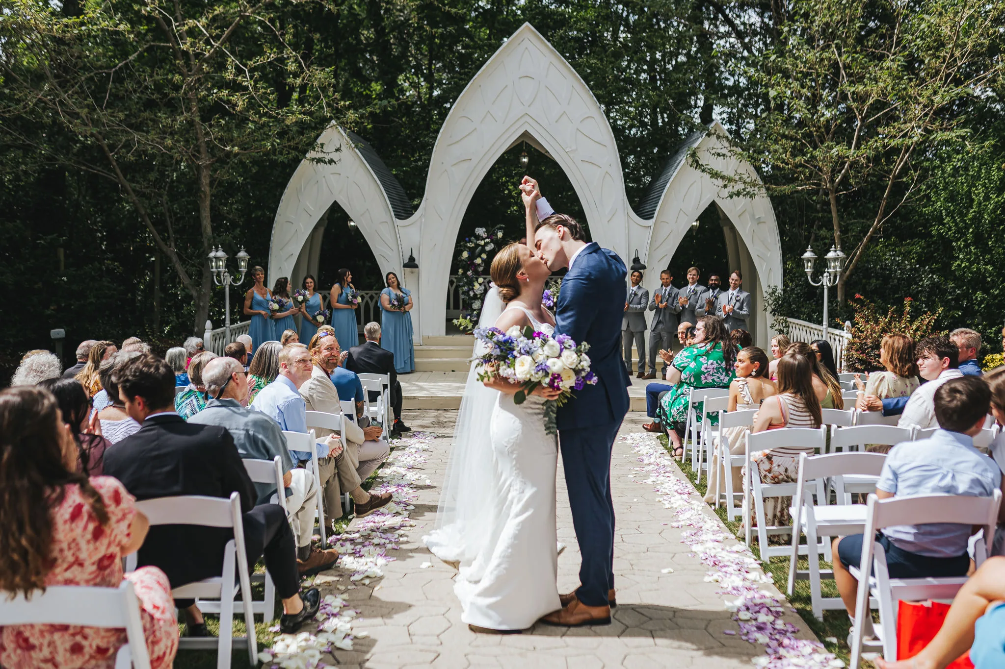 Wedding Ceremony: a kiss with her bouquet up as they walk back up the aisle, at their wedding at The Wildflower 301 in Greensboro, GA