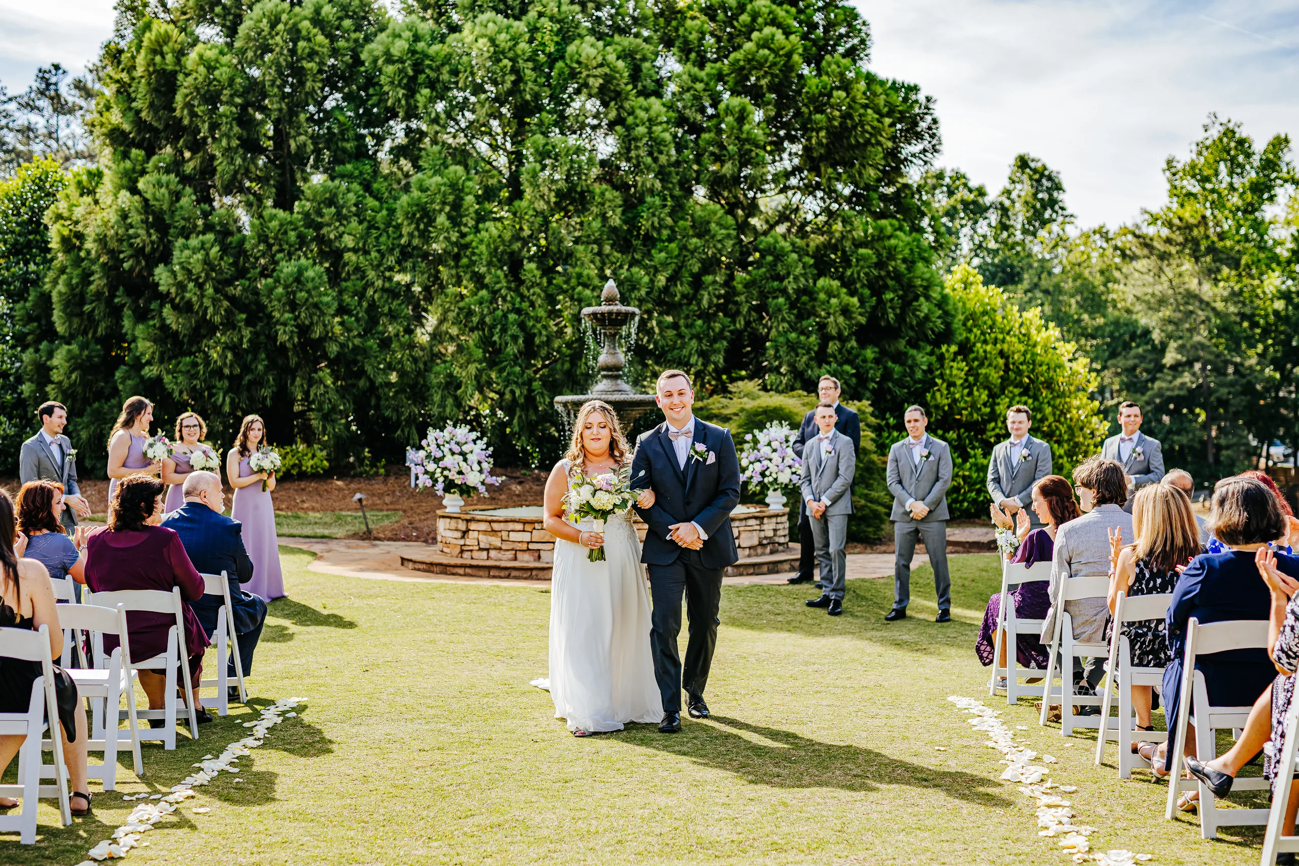 Wedding Ceremony: walking down the aisle between the guests at their wedding at the Country Club of Roswell in Roswell, GA