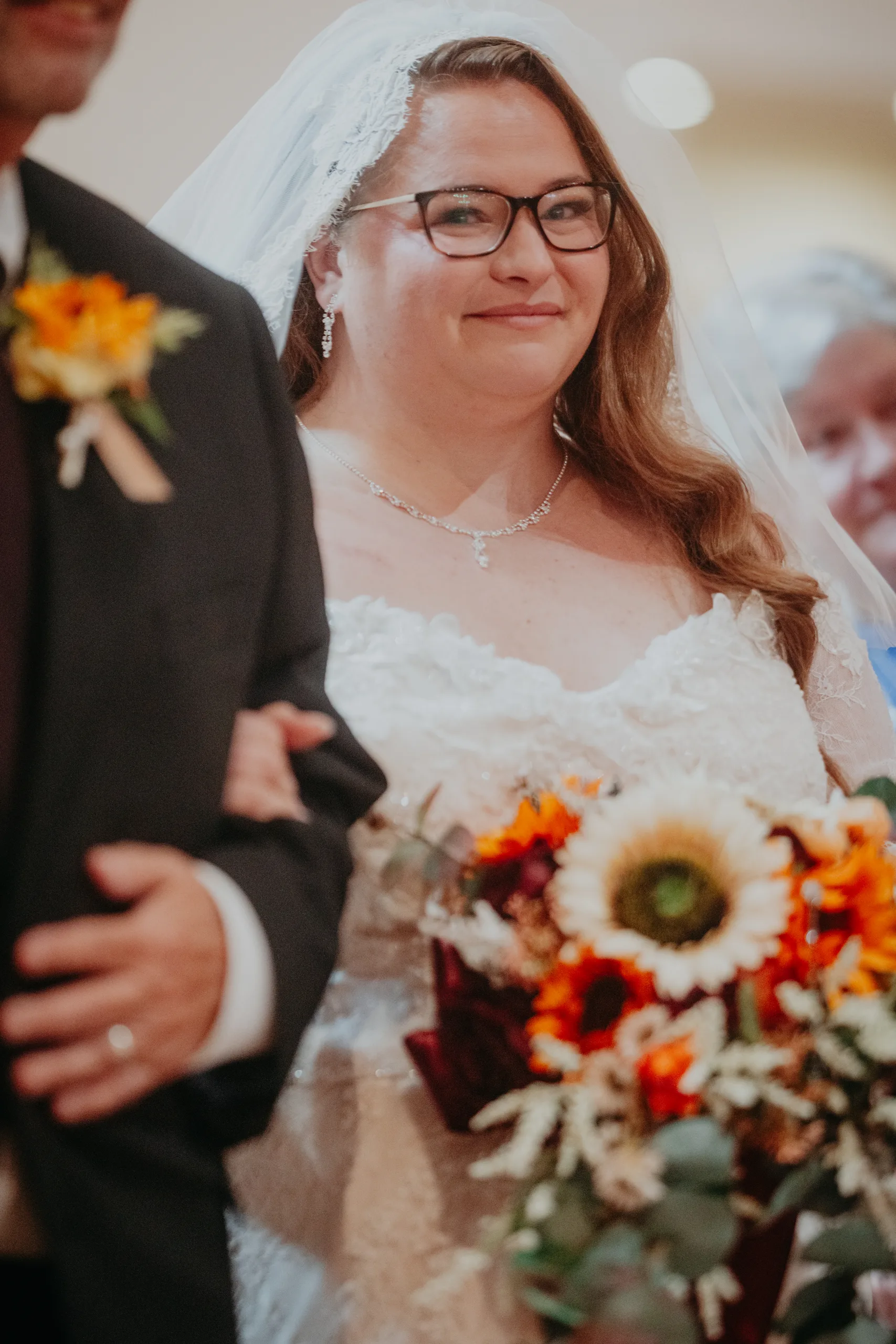 Wedding Ceremony: the bride on her dad's arm with her sunflower bouquet, at their wedding at St. Lawrence Catholic Church in Lawrenceville, GA