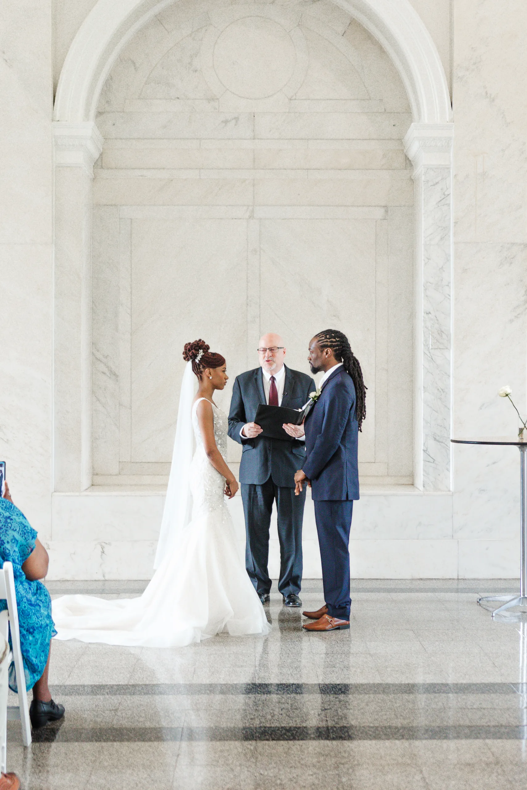 Wedding Ceremony: exchanging vows under the marble arch, at their wedding at the Historic DeKalb Courthouse in Decatur, GA