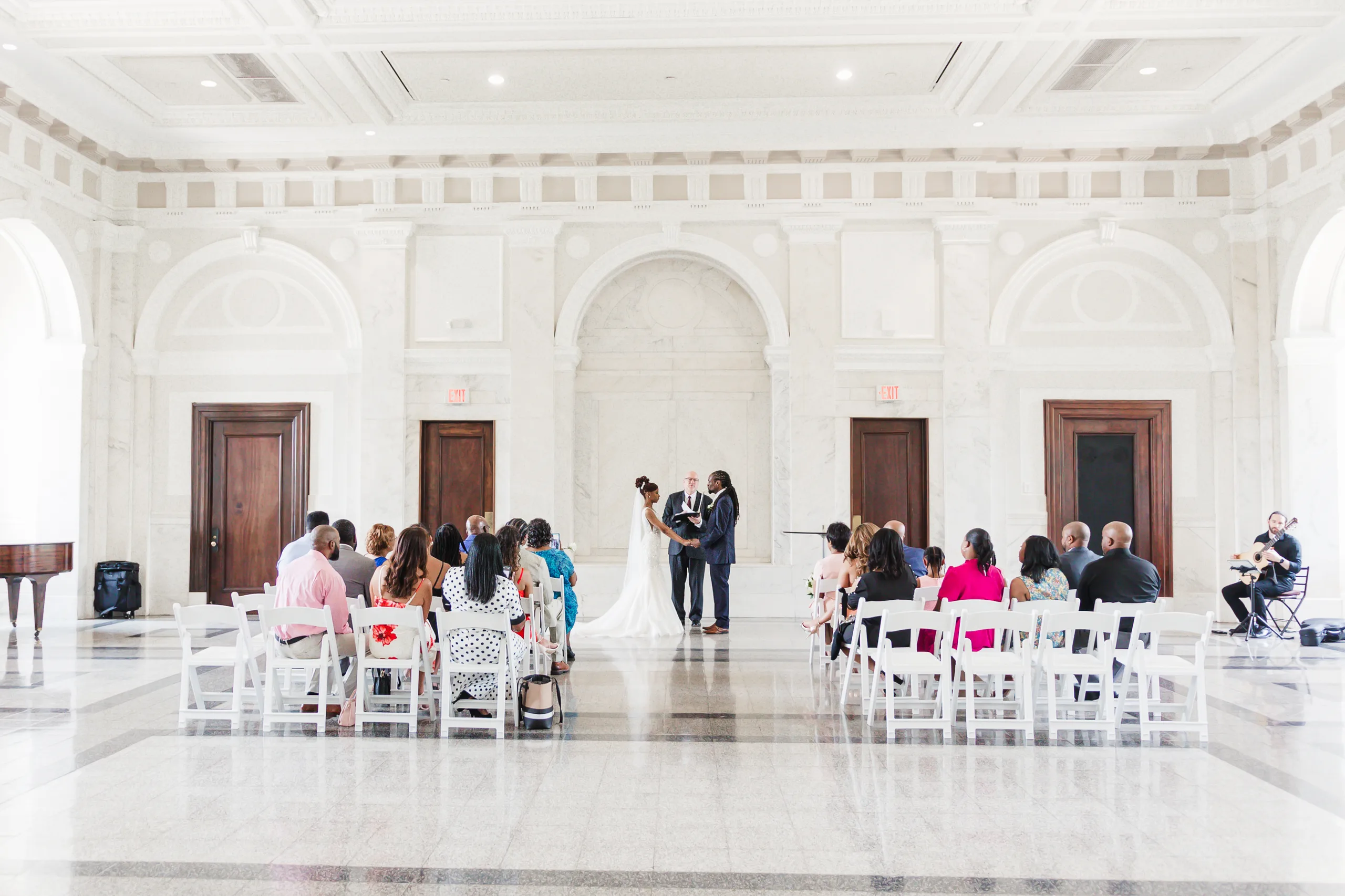 Wedding Ceremony: the full courtroom during the ceremony, the guitarist to one side, at their wedding at the Historic DeKalb Courthouse in Decatur, GA