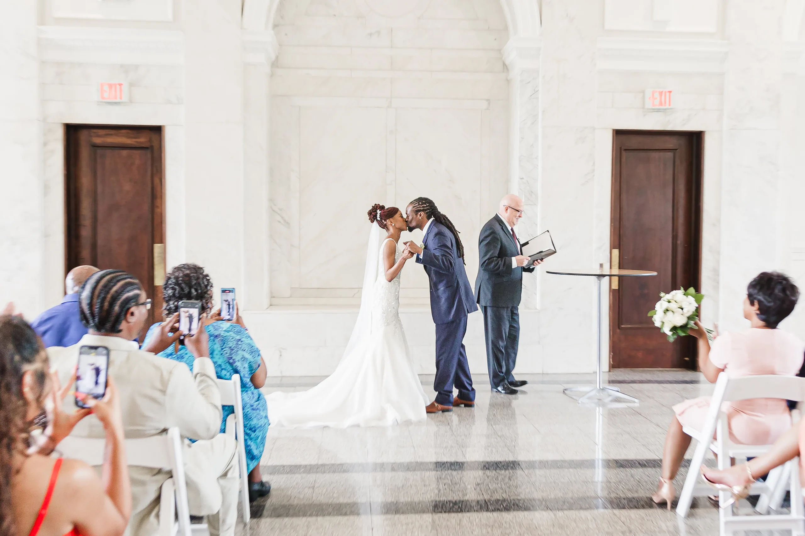 Wedding Ceremony: the first kiss as guests take photos, at their wedding at the Historic DeKalb Courthouse in Decatur, GA