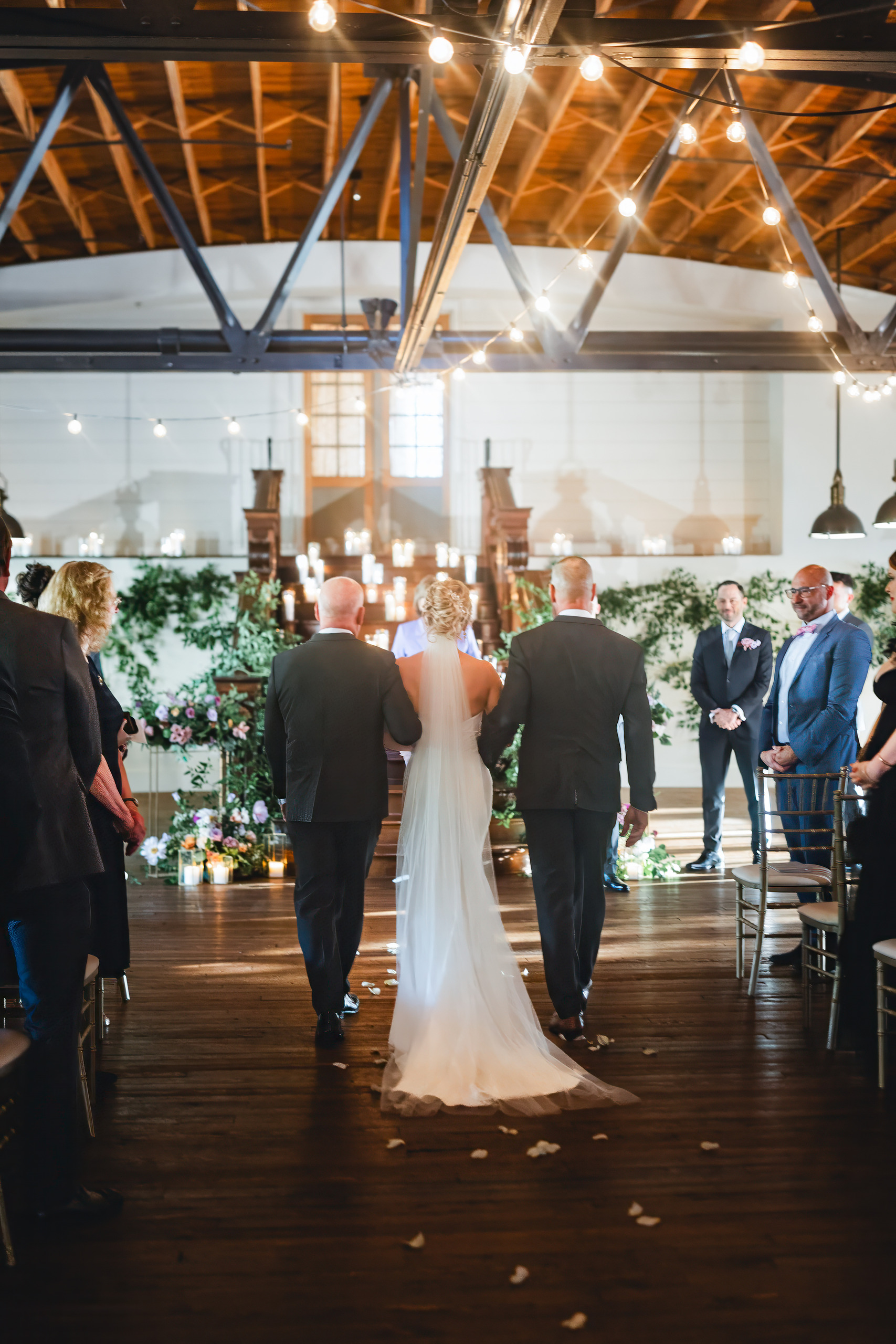 Processional: walking her down the aisle between them, at their wedding at Summerour Studio in Atlanta, GA