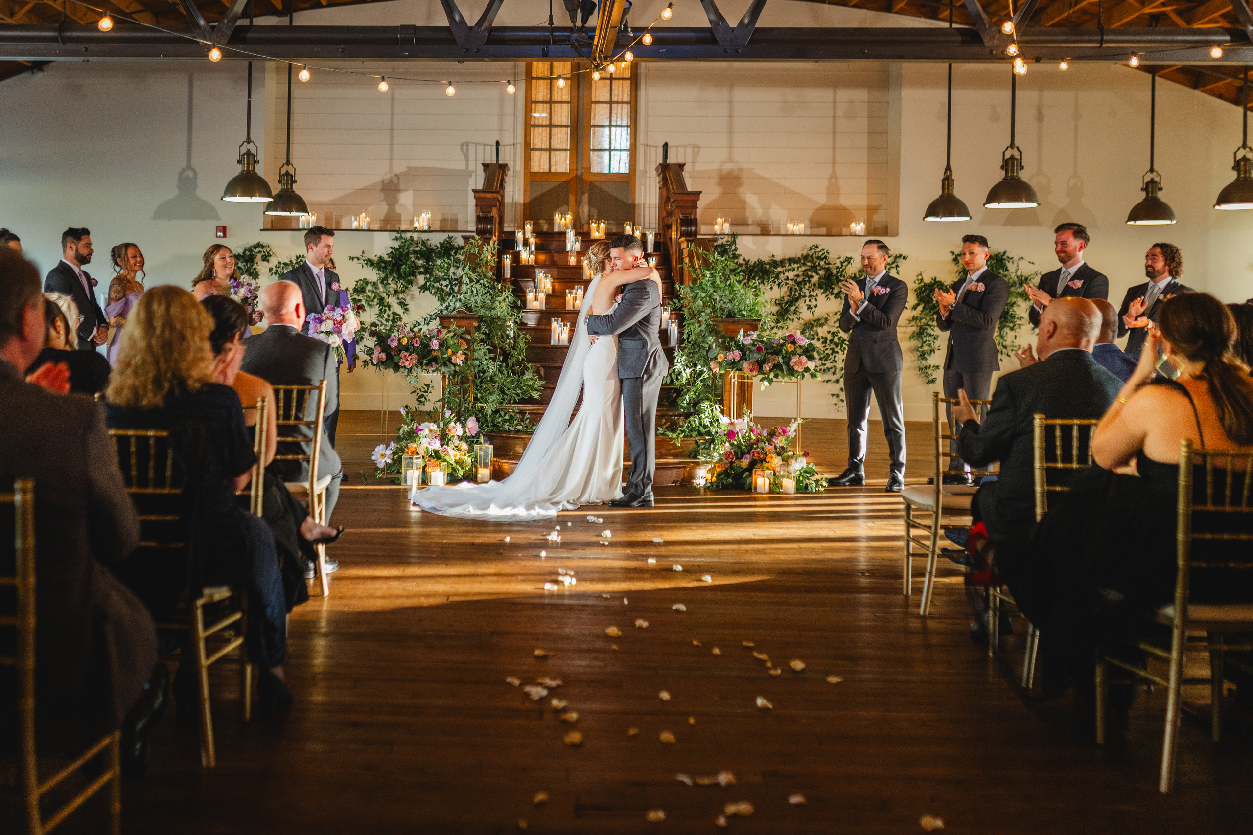 Wedding Ceremony: the first kiss as the room comes to its feet, at their wedding at Summerour Studio in Atlanta, GA