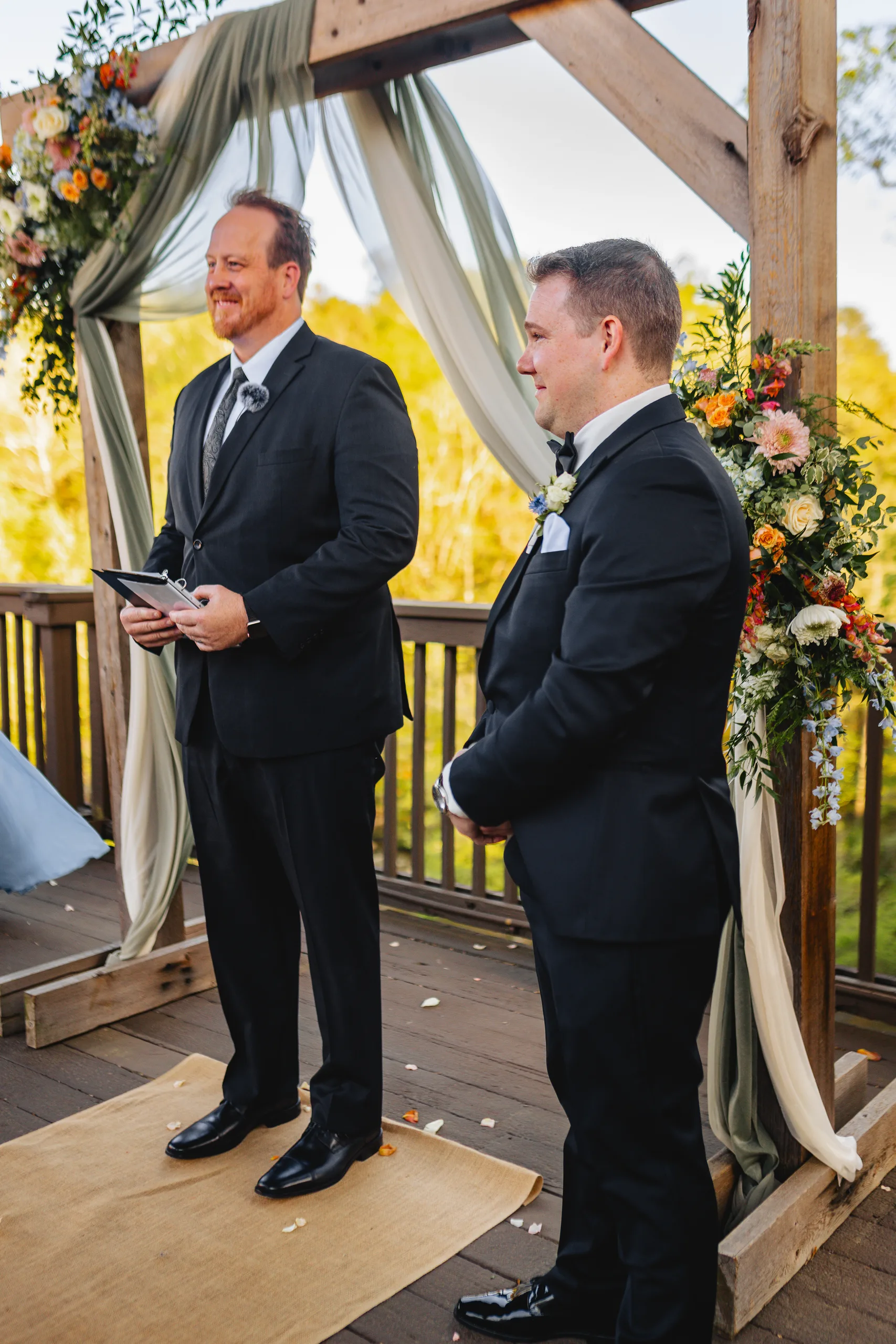 Wedding Ceremony: the groom waiting with the officiant under the arch at their wedding at Ivy Hall at Roswell Mill in Roswell, GA