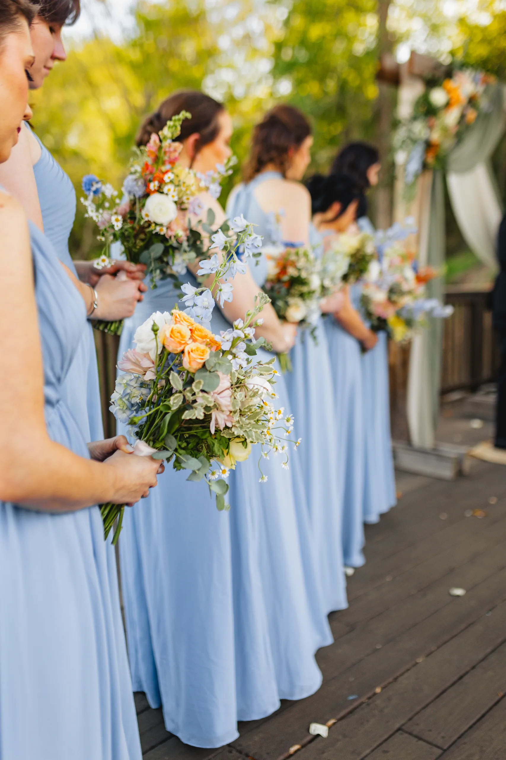 Wedding Ceremony: bridesmaids in dusty blue with their bouquets at their wedding at Ivy Hall at Roswell Mill in Roswell, GA