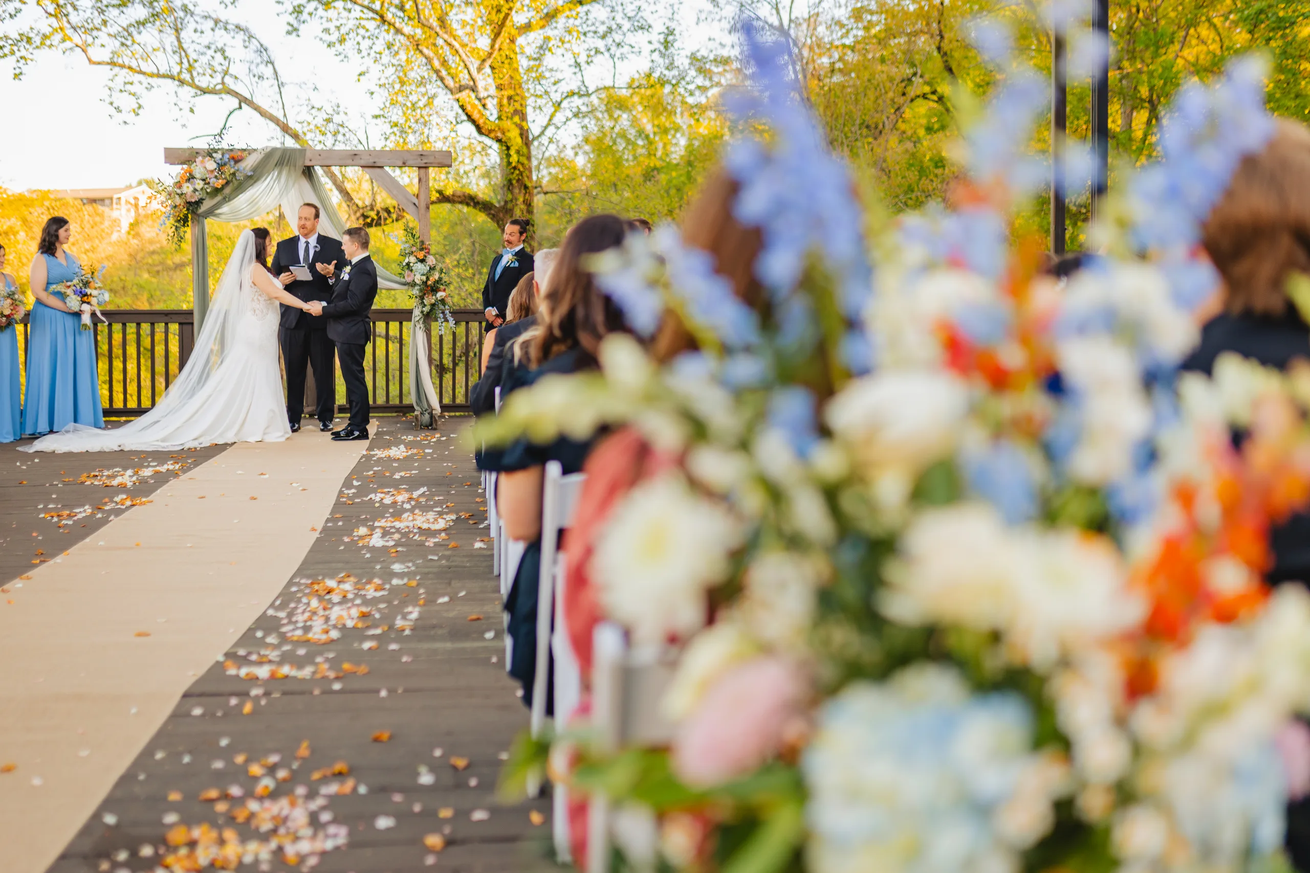 Wedding Ceremony: the ceremony seen through the aisle flowers at their wedding at Ivy Hall at Roswell Mill in Roswell, GA